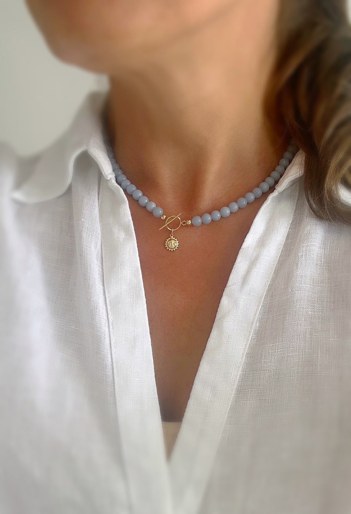 Angelite beaded necklace with a gold sun face charm 