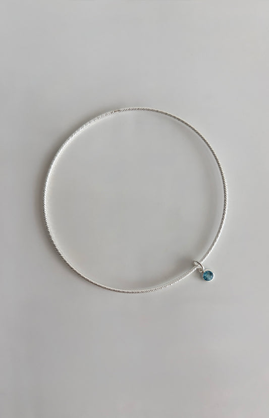 A beautiful Sterling Silver bangle, made with a sparkle finish adorned with your choice of a single crystal Birthstone charm  