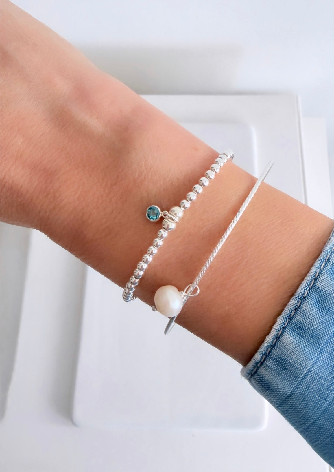 A beautiful Sterling Silver bangle, made with a sparkle finish adorned with your choice of a single crystal Birthstone charm  