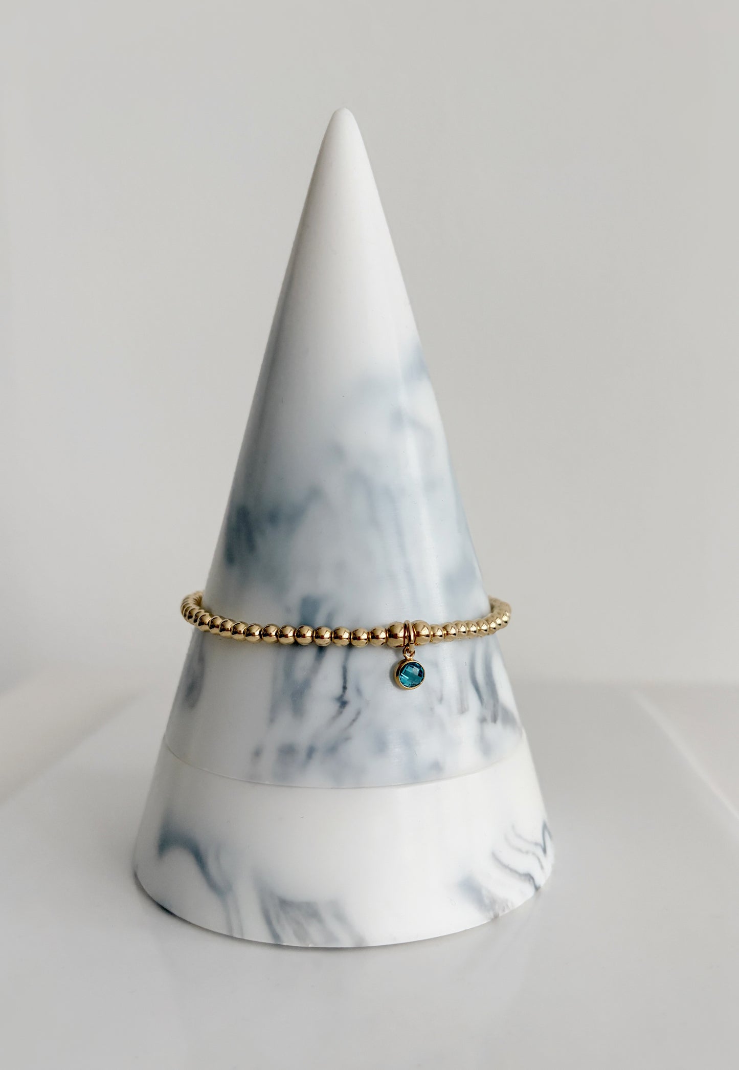 A sterling silver or gold filled beaded bracelet with a crystal birthstone charm. Additional charms can be added to represent family members or loved ones 