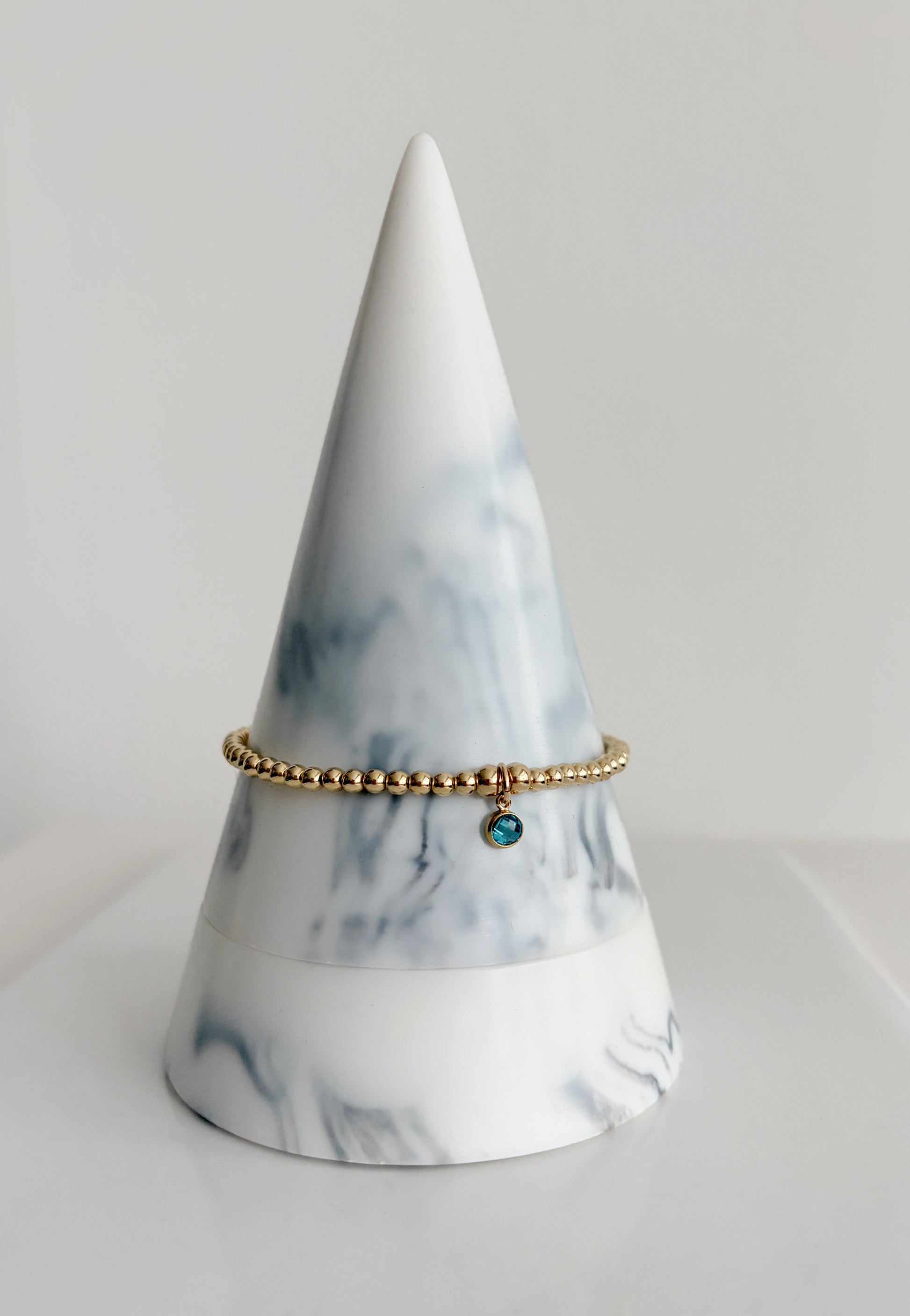 A sterling silver or gold filled beaded bracelet with a crystal birthstone charm. Additional charms can be added to represent family members or loved ones 