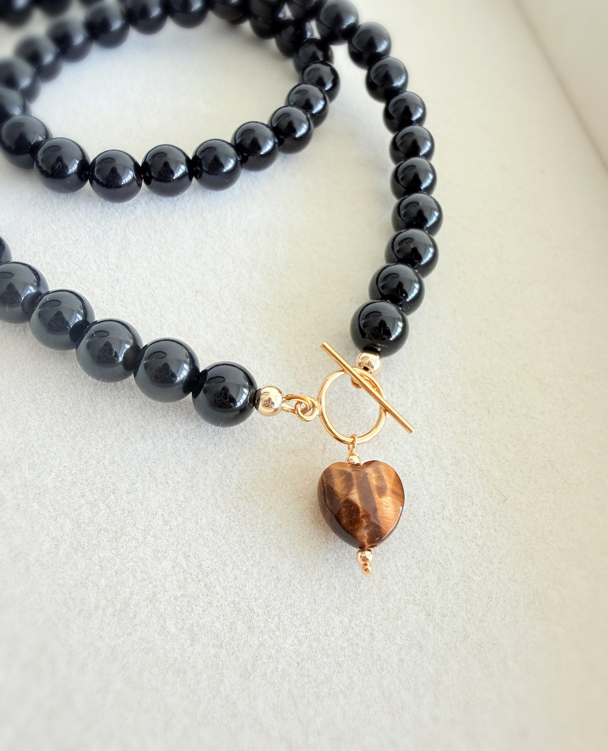 A stunning Black Onyx necklace featuring a faceted heart shaped Tiger’s Eye bead.

The necklace is finished with a toggle clasp in either a Gold filled or Sterling Silver finish. The necklace length is approximately 17”