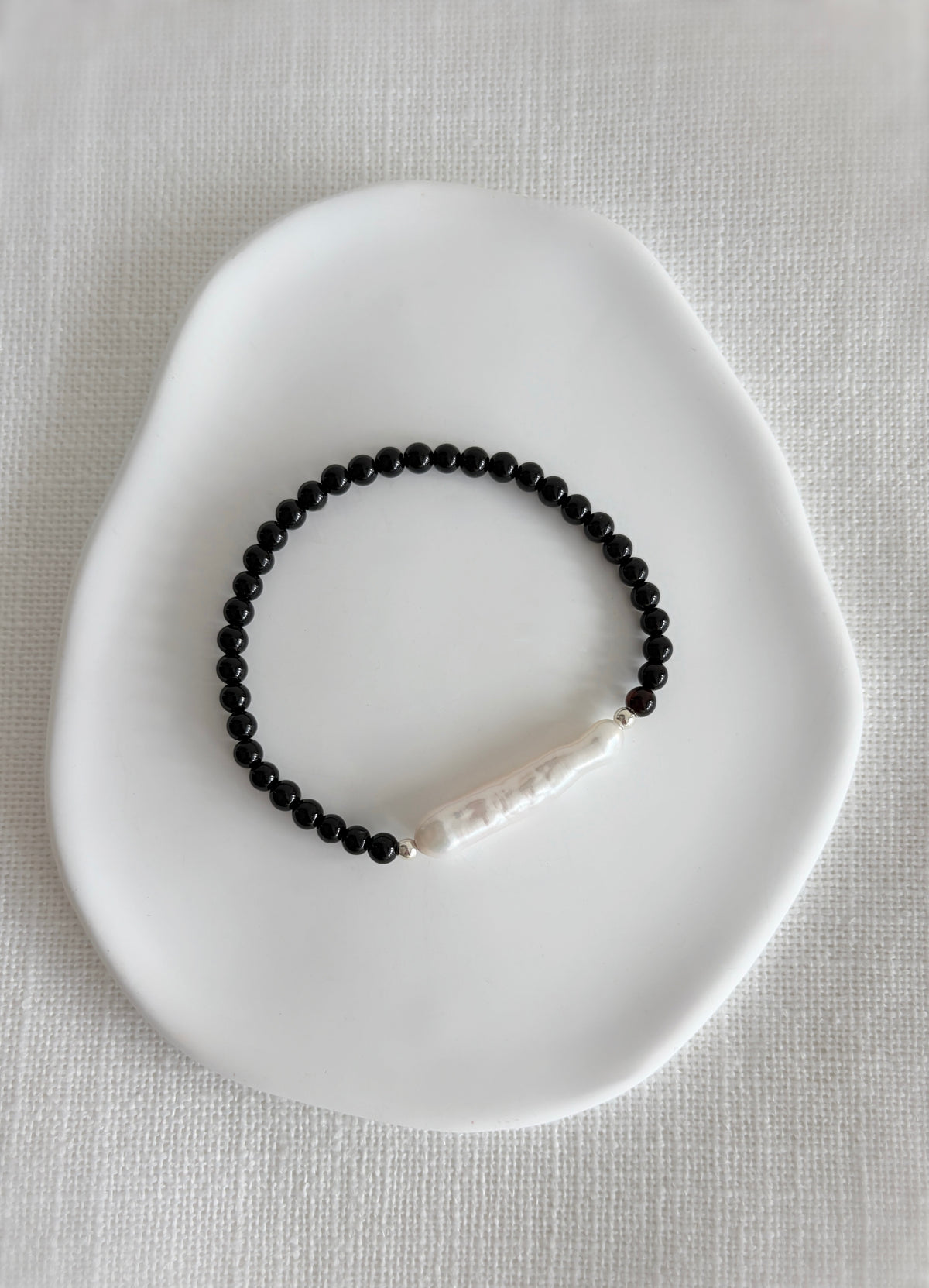 A striking Black Onyx bracelet featuring a Biwa Freshwater Pearl hand threaded on a high quality stretch cord. Choose from either a Sterling silver, or Gold Filled finish.
