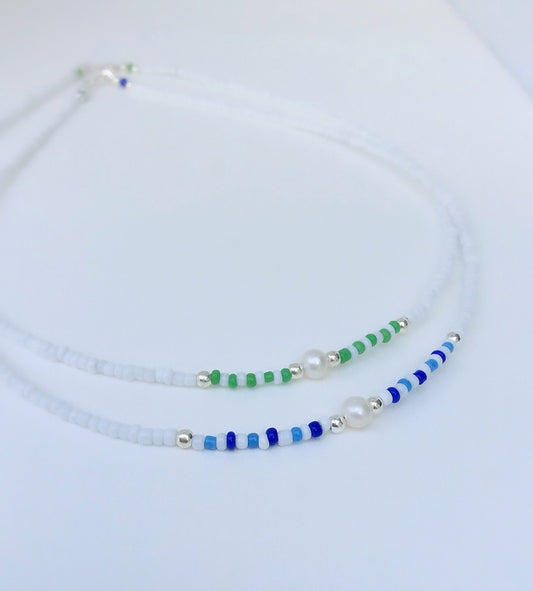 Two seed bead necklaces, one with blue beads and the other with green, both interspersed with silver beads and white pearls