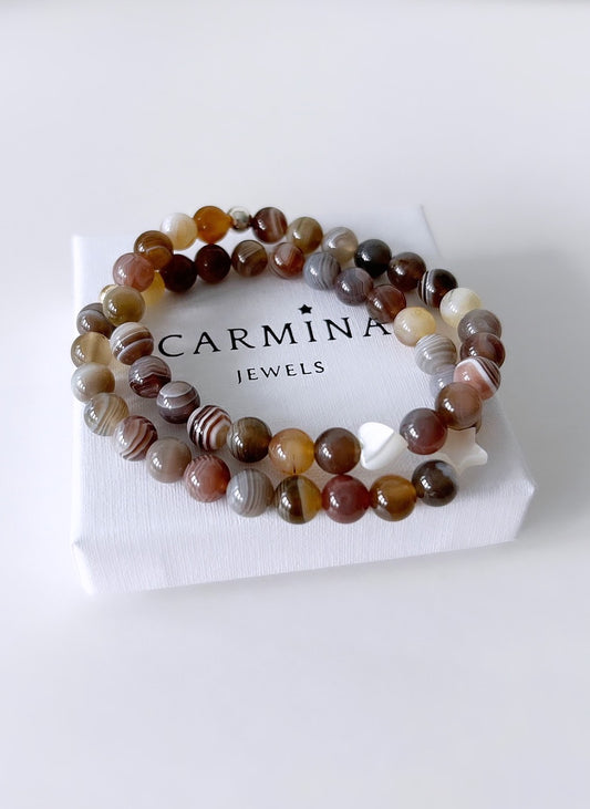 A Botswana agate beaded bracelet with varying shades of brown and white, in a white box with 'Carmina Jewels' branding.