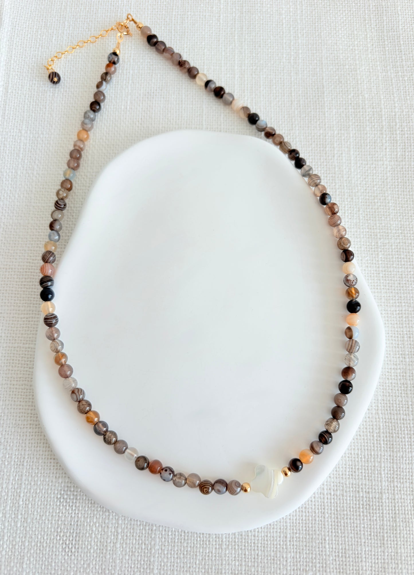 A beautiful Semi precious beaded Botswana Agate necklace with a central Mother of Pearl clover bead. 

Crafted with high quality semi precious beads, each one as beautiful as it is unique.

Available with a choice of either a Sterling Silver or Gold filled clasp. The necklace length is 16” with an 2” extender, finished at the end with a precious bead. 
