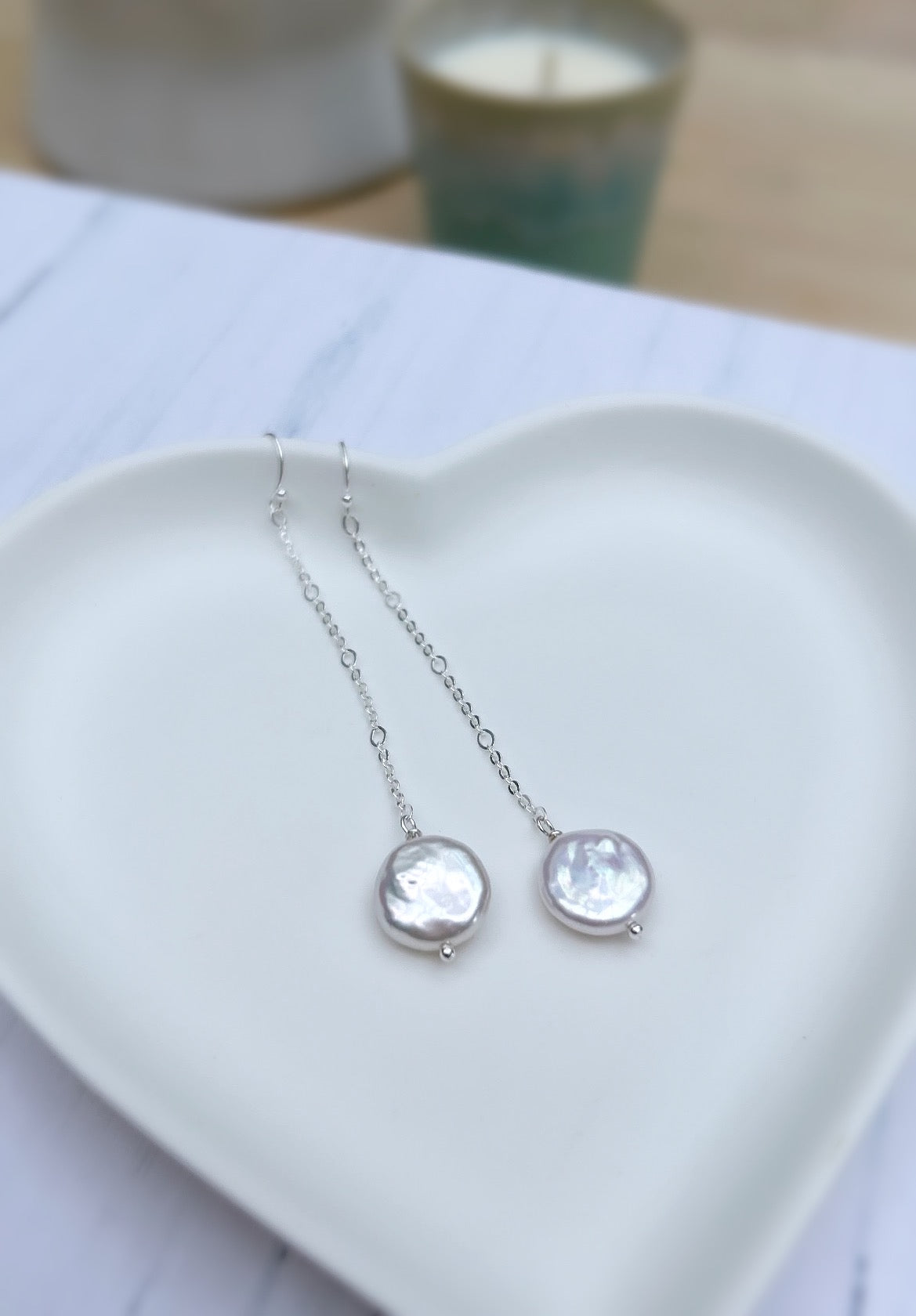 Beautiful dangle pearl earrings with coin shaped Freshwater Pearls. The earrings are on a hook ear fastening with the pearls hanging from a delicate Sterling Silver figaro chain.