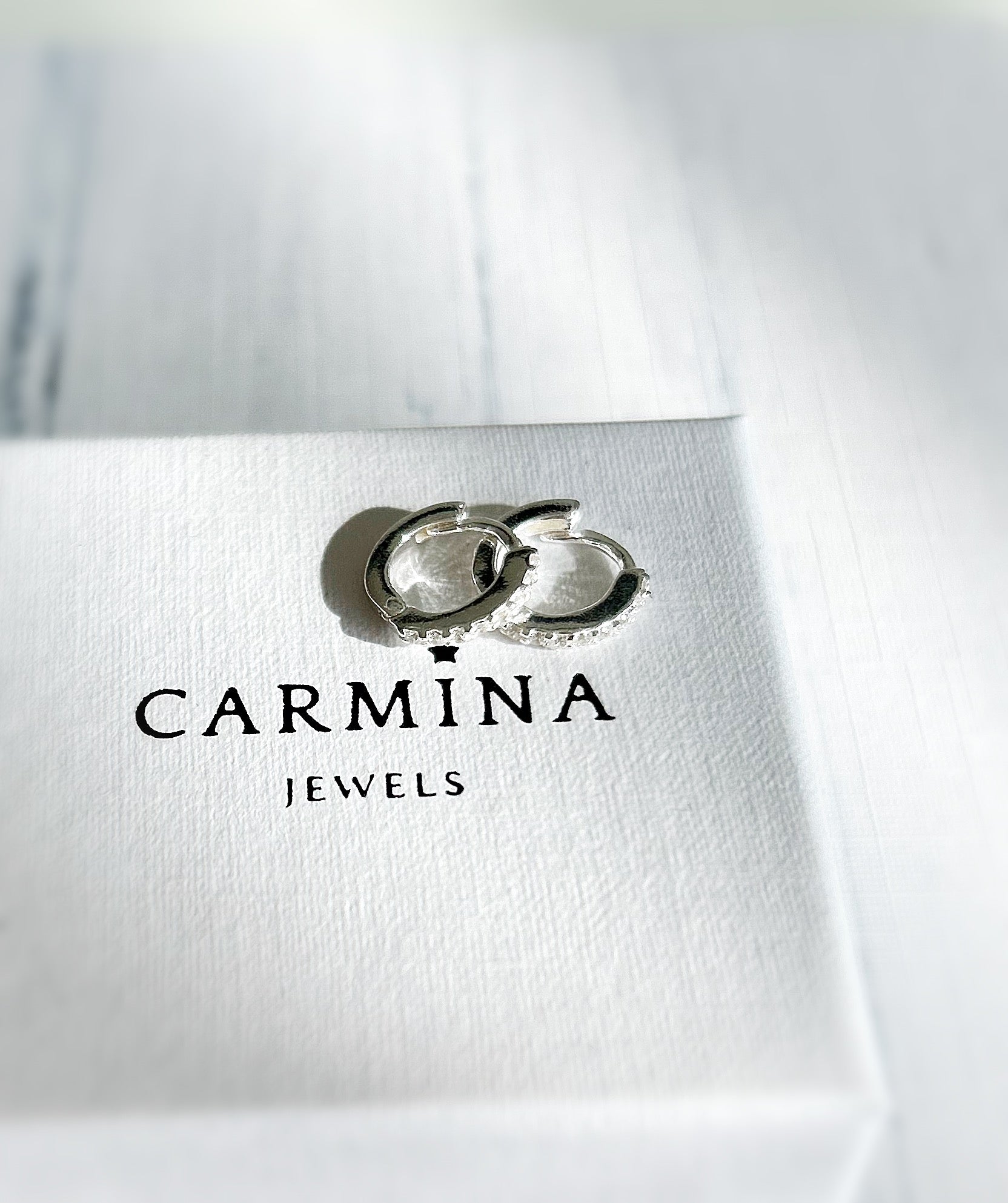 A pair of sterling silver huggie hoop earrings dotted with CZ crystals. 