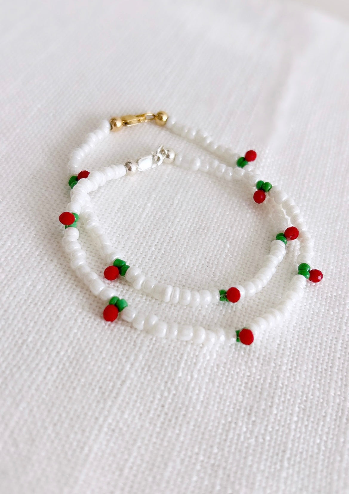 A sweet seed bead Cherry bracelet hand threaded with Miyuki glass and crystal glass faceted beads finished with a choice of a Sterling Silver or Gold Filled clasp. 

This dainty piece features a pretty row of cherries design on a white beaded base. 