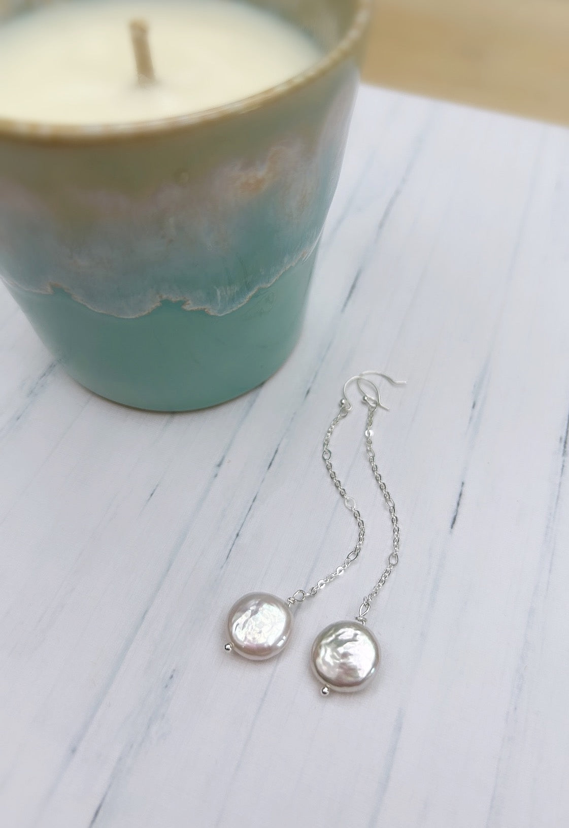 Beautiful dangle pearl earrings with coin shaped Freshwater Pearls. The earrings are on a hook ear fastening with the pearls hanging from a delicate Sterling Silver figaro chain.