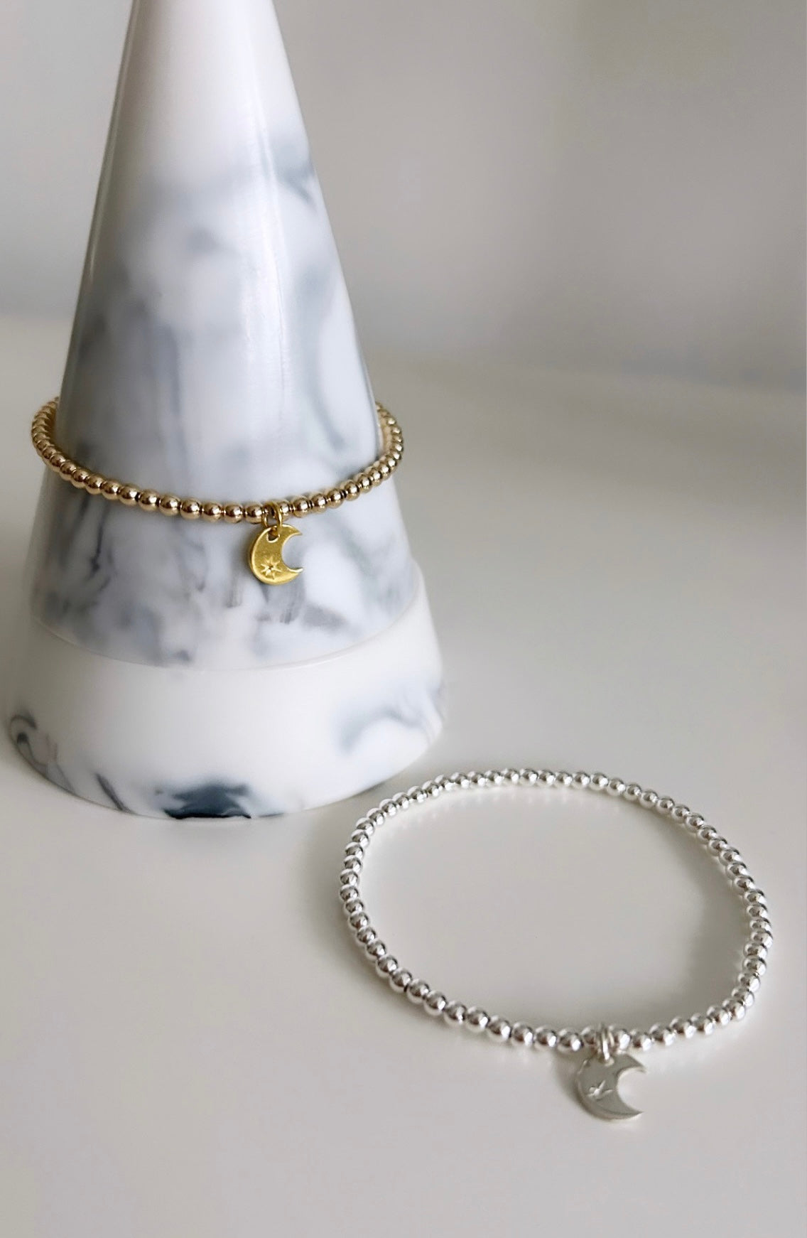 A two-layered charm bracelet with a crescent moon design on the top layer and a star-shaped charm on the bottom,