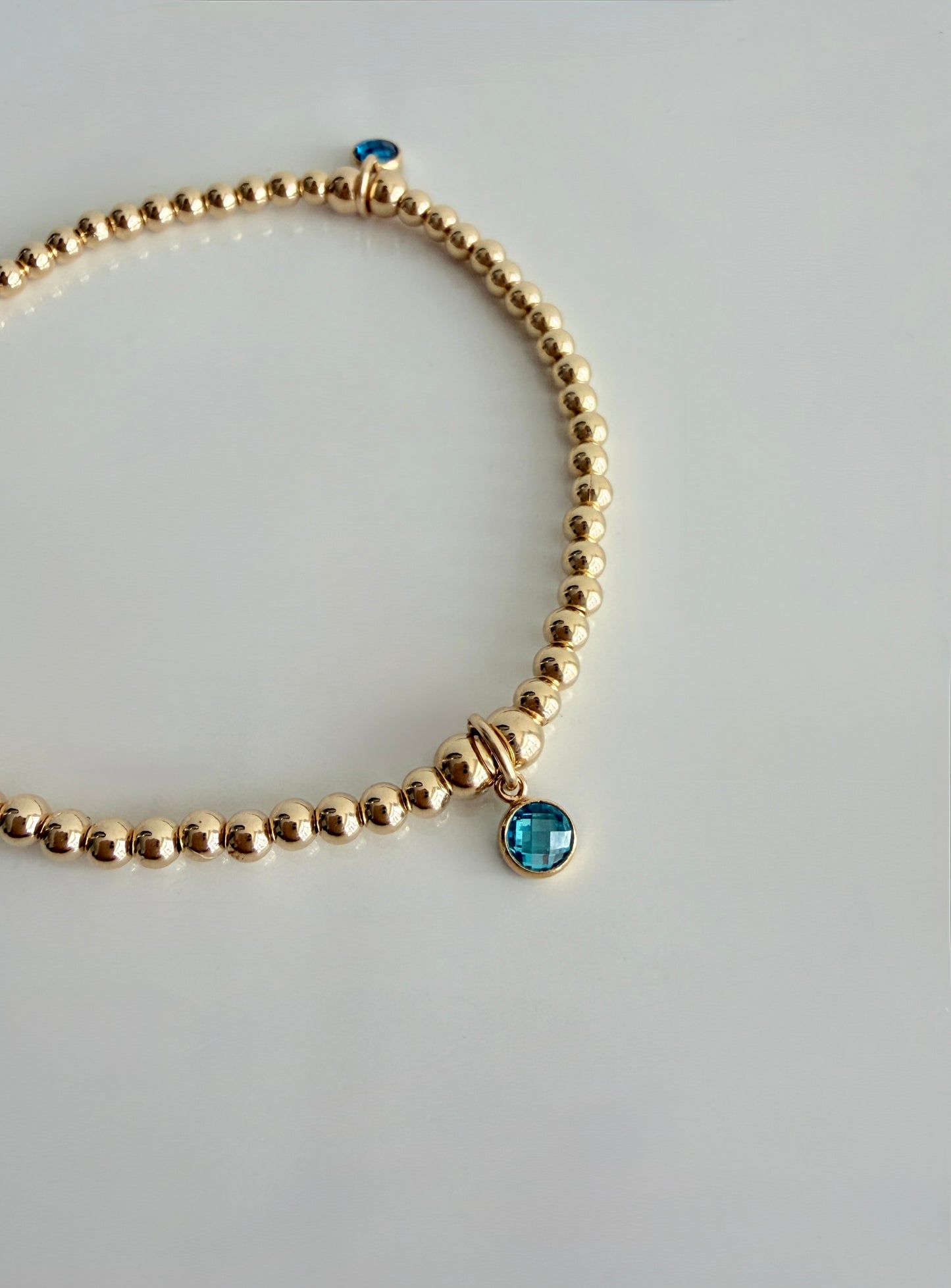 A sterling silver or gold filled beaded bracelet with a crystal birthstone charm. Additional charms can be added to represent family members or loved ones 