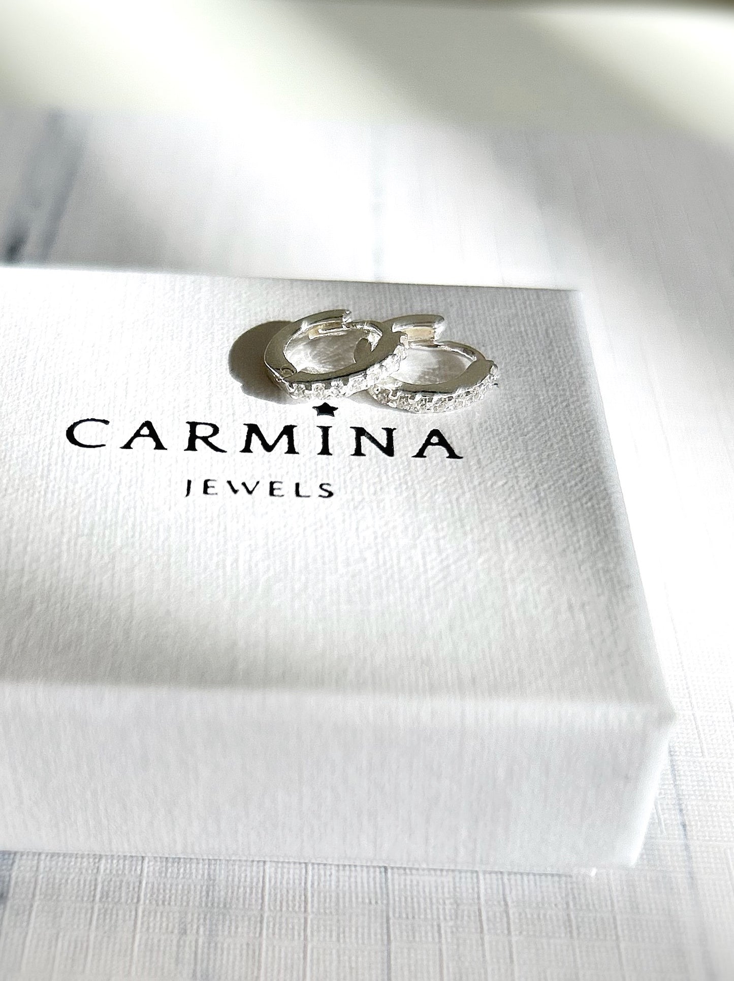 A pair of sterling silver huggie hoop earrings dotted with CZ crystals. 