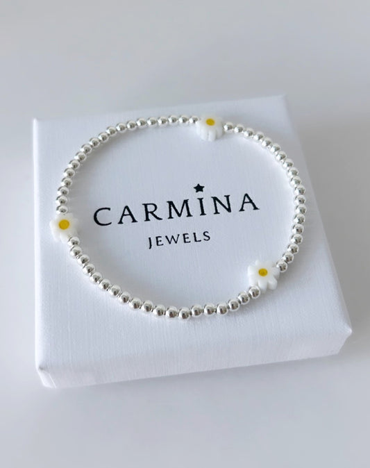 A white daisy bracelet with yellow accents, made of Murano glass and sterling silver, presented in a box with 'Carmina Jewels' branding.