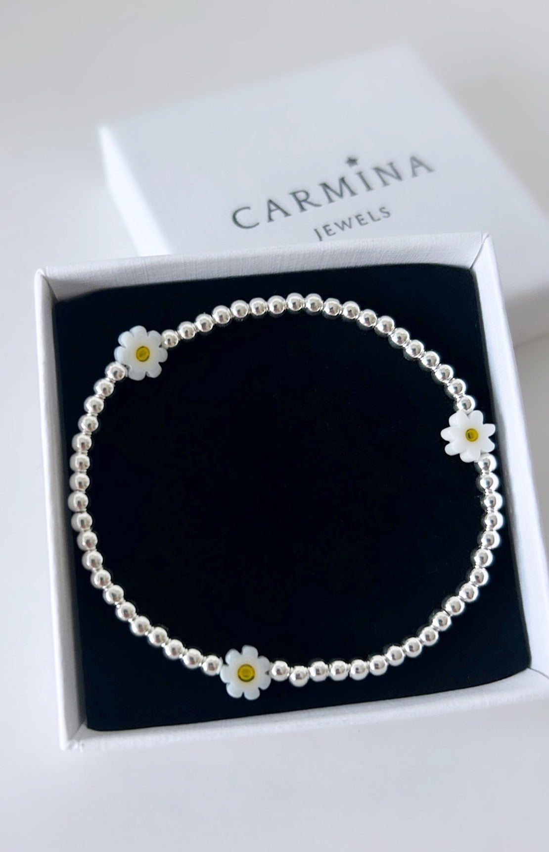 Pretty handmade Murano glass daisy bracelet with Sterling Silver round beads. The bracelet is on a stretch cord with spaced out daisies beads.