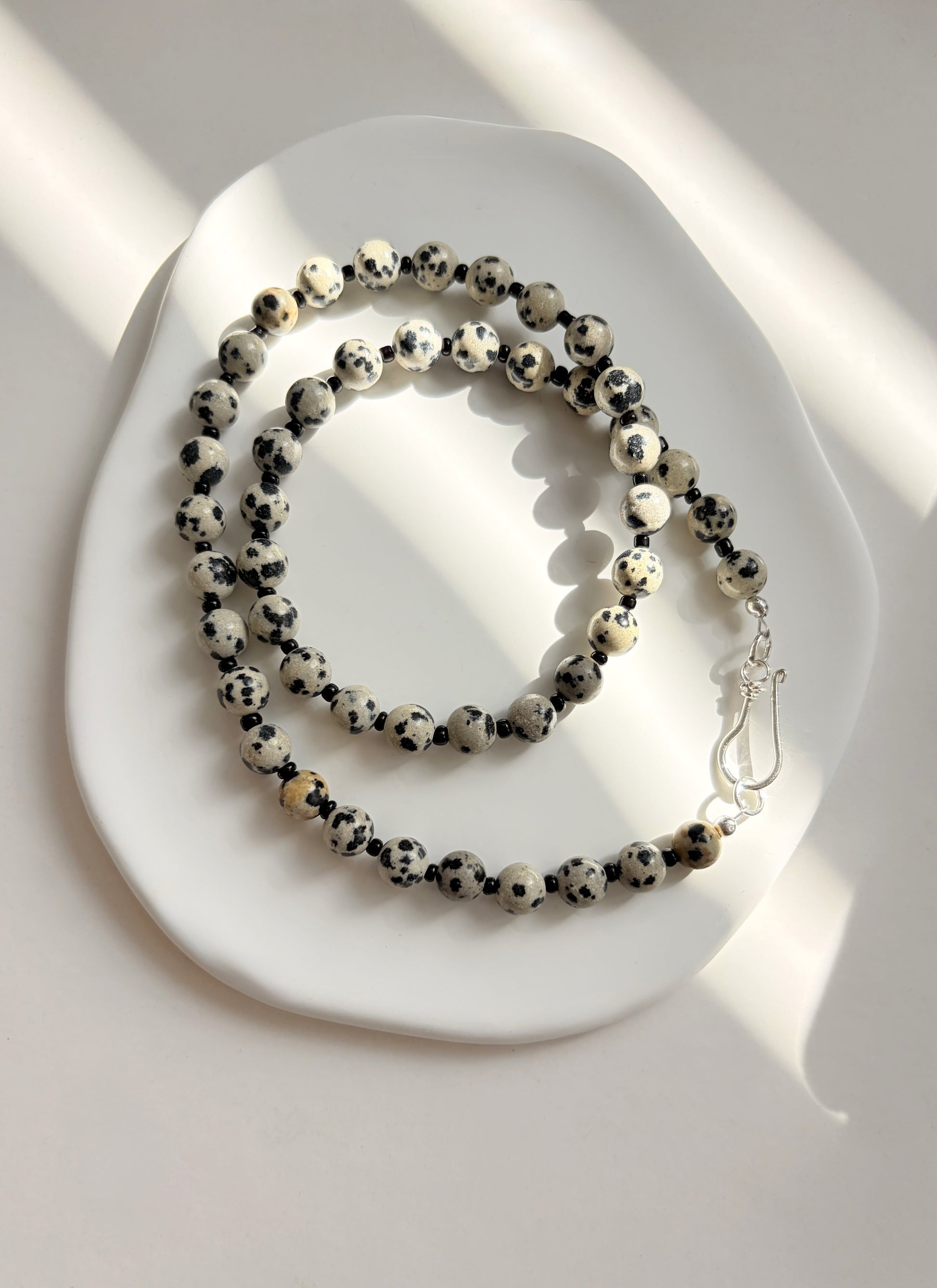 Made using semi precious Dalmatian Jasper beads.   

The necklace is finished with a decorative ‘S’ style clasp fastener in either a Gold Vermeil or Sterling Silver finish. The necklace length is 18”.
