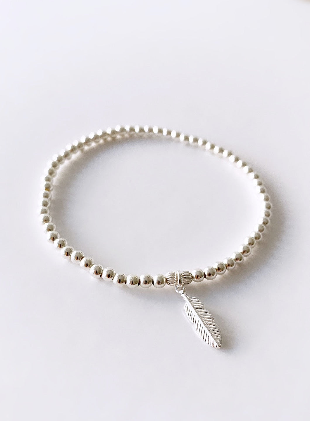 Beautiful Sterling Silver beaded bracelet on a stretch cord with a delicate silver Feather charm.
