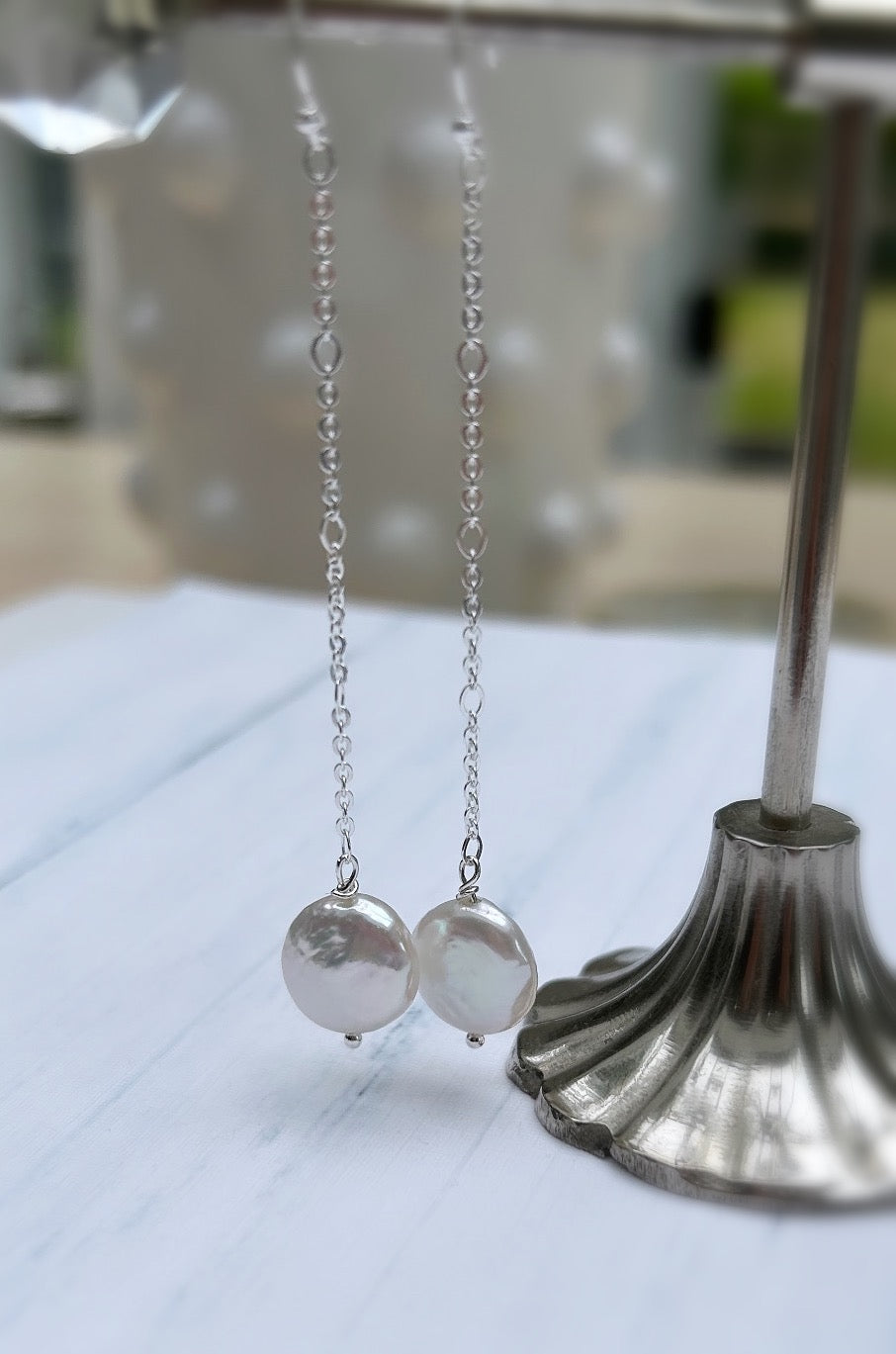Beautiful dangle pearl earrings with coin shaped Freshwater Pearls. The earrings are on a hook ear fastening with the pearls hanging from a delicate Sterling Silver figaro chain.