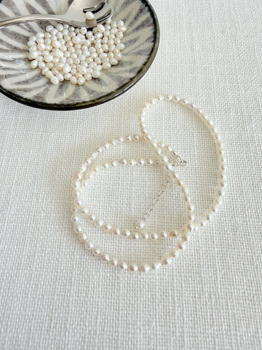Freshwater rice Pearl choker style Necklace with a Sterling Silver or Gold Filled lobster clasp.

The necklace measures 15” and is made using rice pearls which measure approximately 3.5-4mm in diameter, and 4-4.5mm in length, with a 2” extender chain finished with a pearl at the end. 
