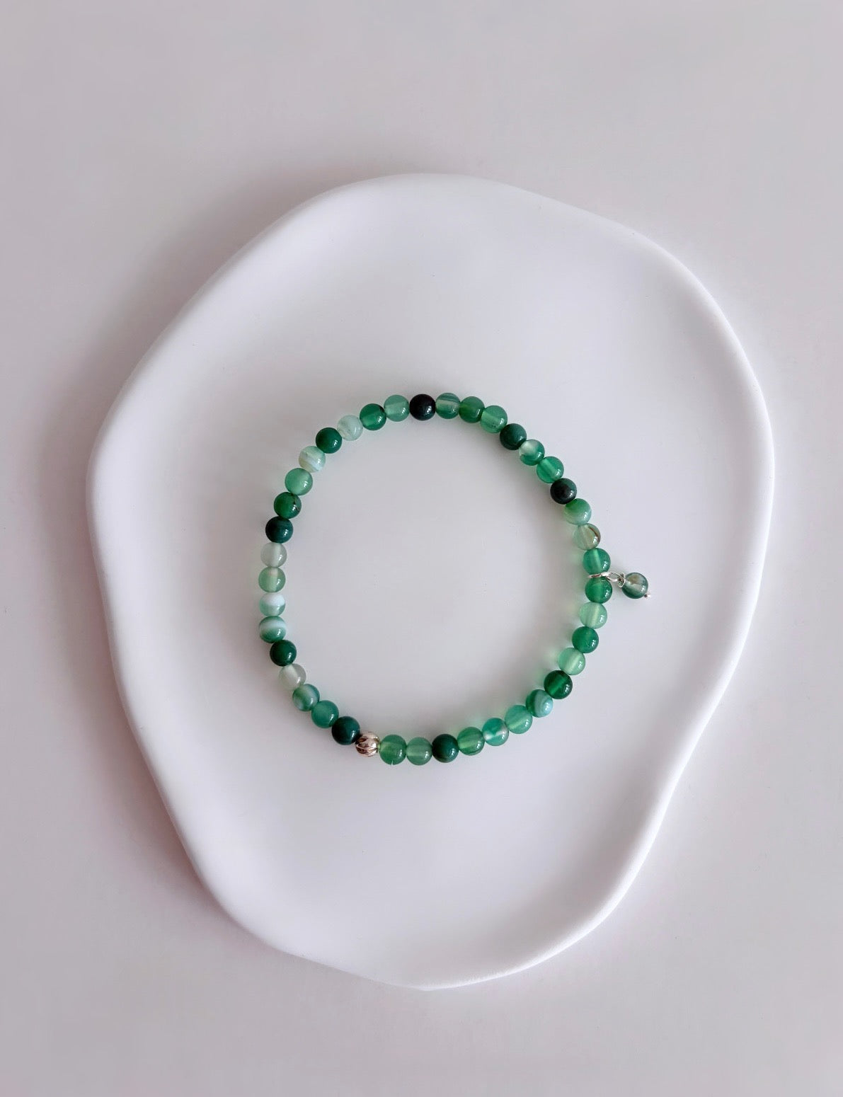 A beautiful semi precious beaded Green Agate stacking bracelet accented with a Sterling Silver twist engraved bead and an agate dangle bead, hand threaded on a durable stretch cord.