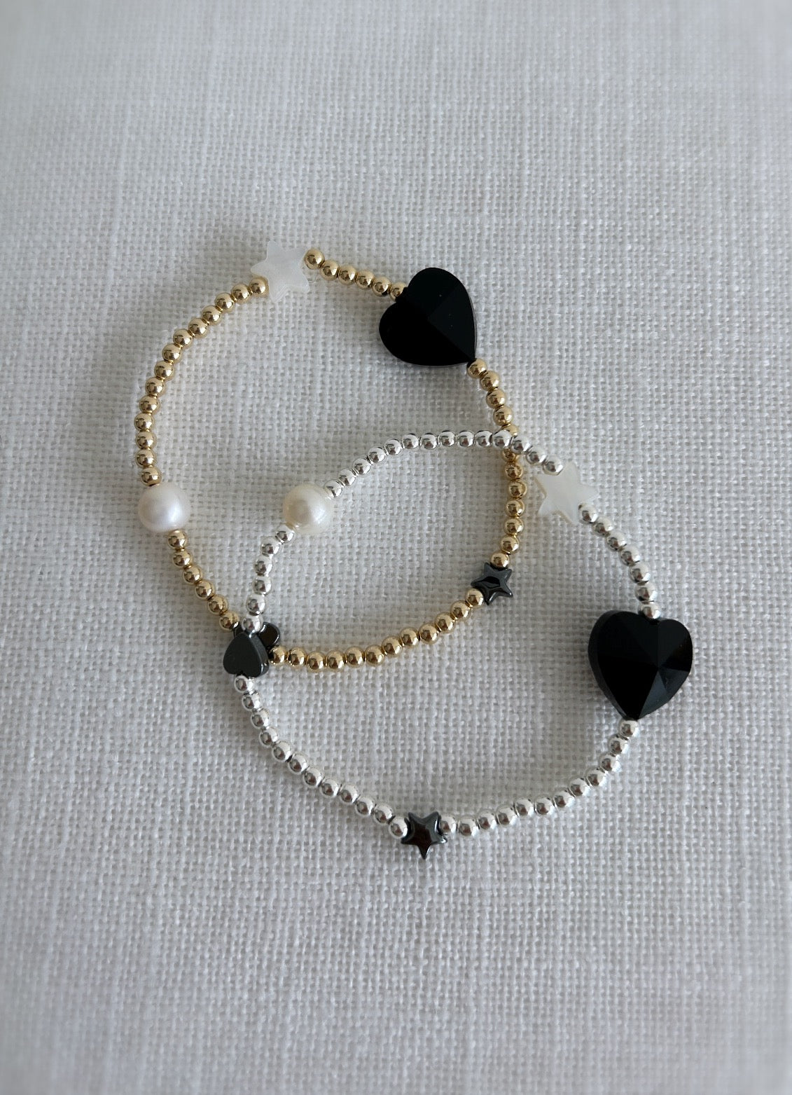 A beautiful stacking bracelet adorned with a charming mix of hearts, stars, and pearls ~ featuring a glass heart bead, a freshwater pearl, a Mother of Pearl heart and star, and a shimmering hematite star.