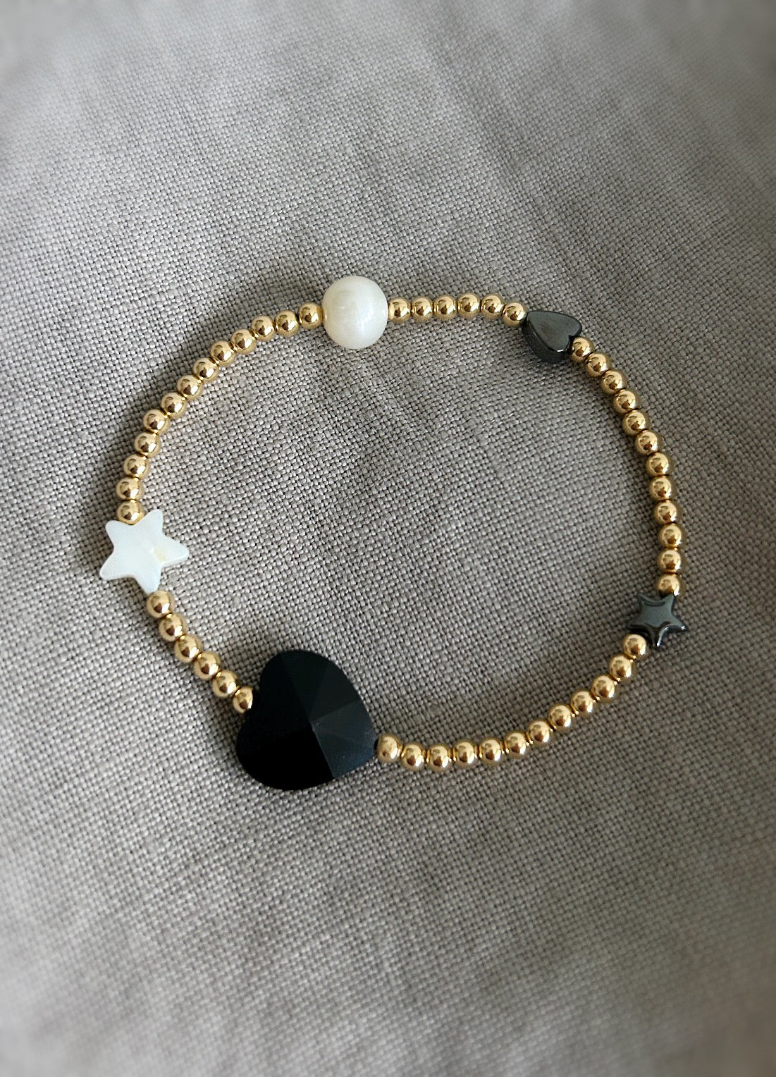 A beautiful stacking bracelet adorned with a charming mix of hearts, stars, and pearls ~ featuring a glass heart bead, a freshwater pearl, a Mother of Pearl heart and star, and a shimmering hematite star.