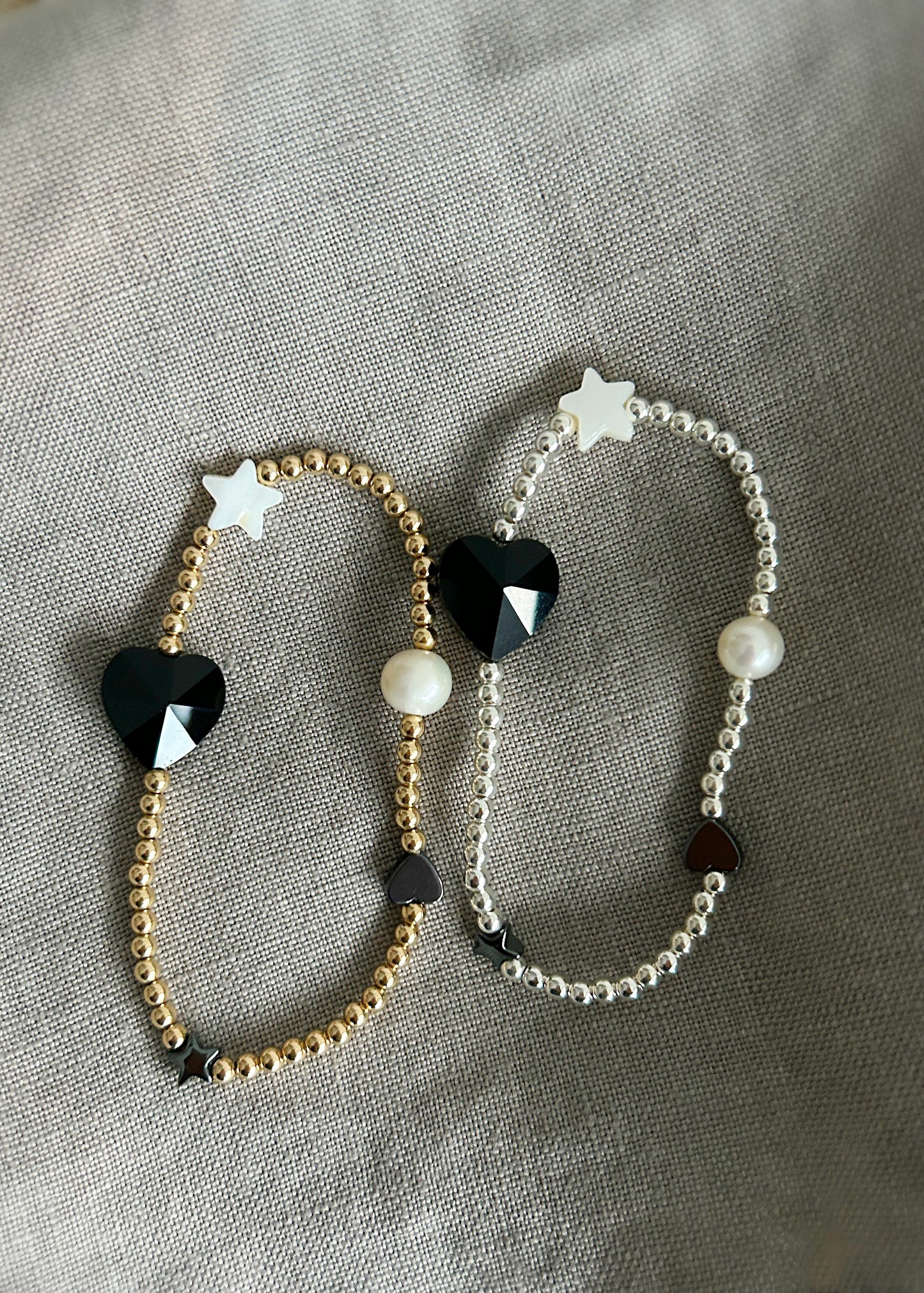 A beautiful stacking bracelet adorned with a charming mix of hearts, stars, and pearls ~ featuring a glass heart bead, a freshwater pearl, a Mother of Pearl heart and star, and a shimmering hematite star.