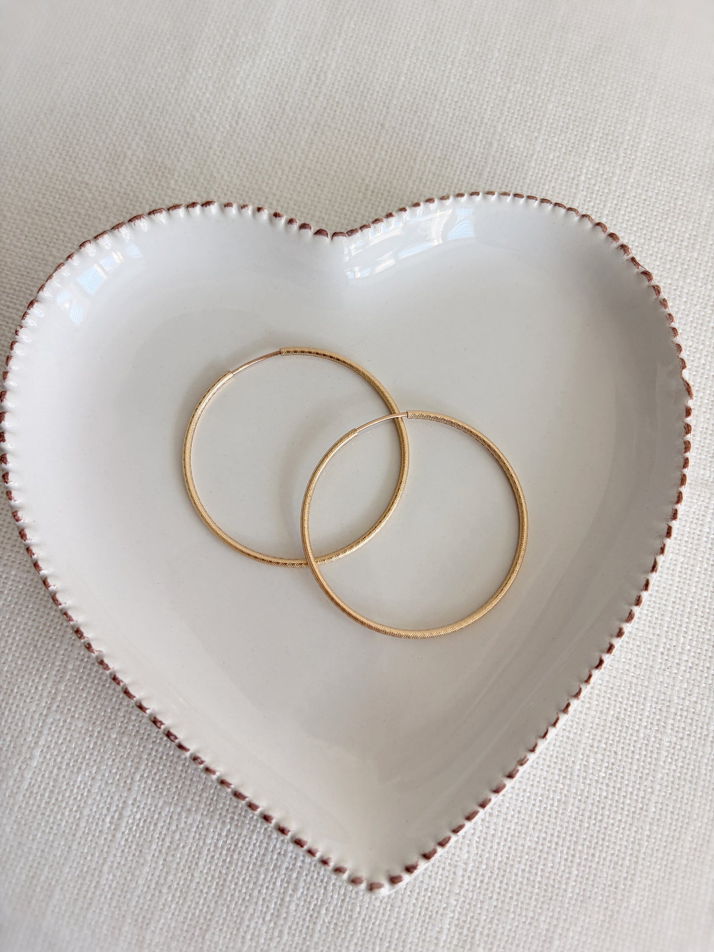 14ct Yellow Gold filled endless hoop earrings feature a timeless design with a textured finish. The spring closure is concealed, creating a seamless endless hoop for a smooth finish.

The hoops are available in either a 30mm or 40mm size. 