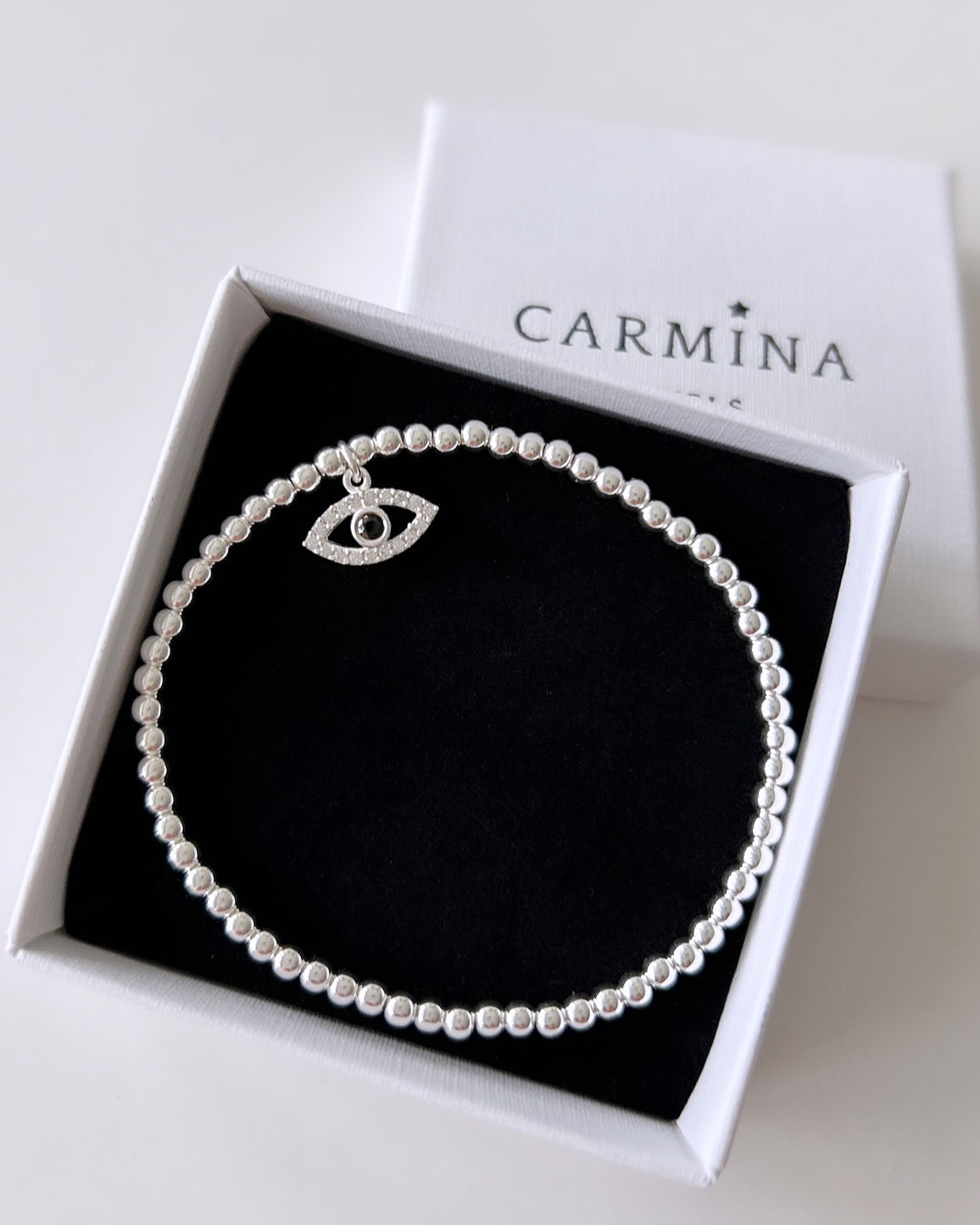 A sterling silver or gold filled beaded stacking bracelet with a lucky 'Evil Eye' charm set with cubic zirconia, presented in a Carmina gift box.