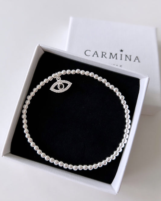 A sterling silver or gold filled beaded stacking bracelet with a lucky 'Evil Eye' charm set with cubic zirconia, presented in a Carmina gift box.