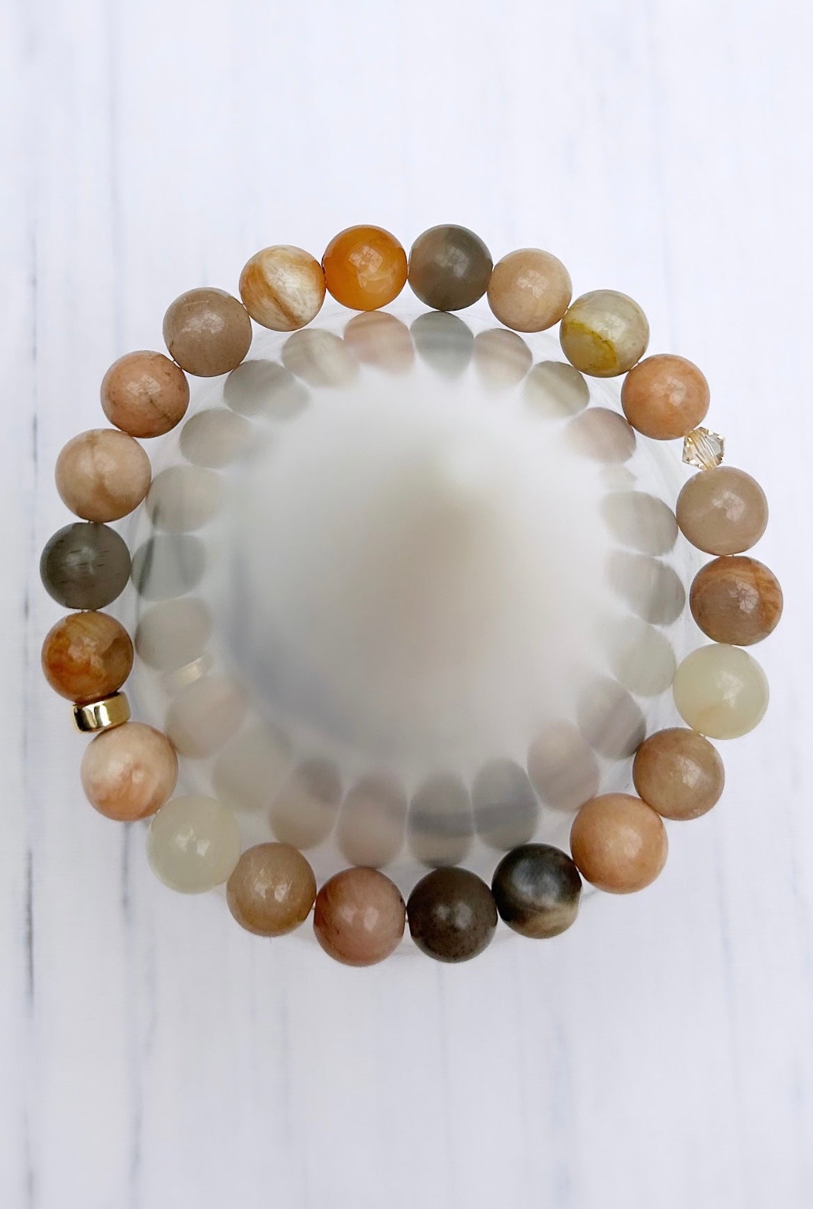 A beaded bracelet with a mix of Moonstone and Swarovski crystal beads, featuring a silver or gold filled spacer bead.