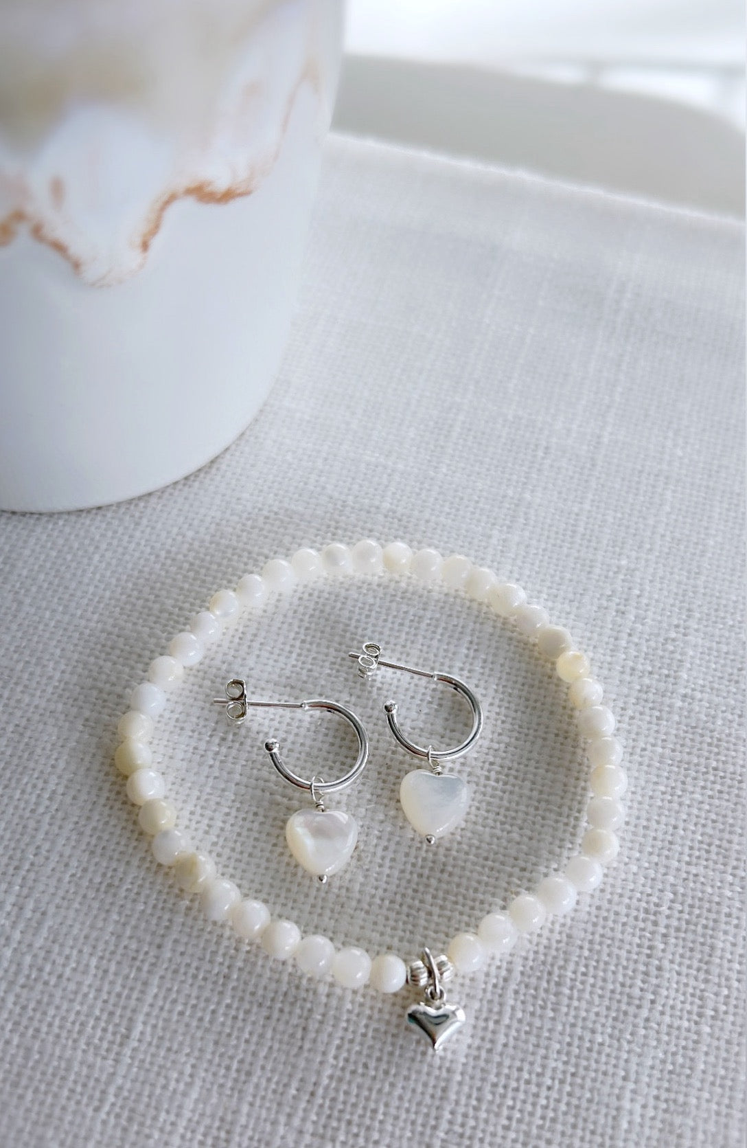 A beautiful Mother of Pearl beaded bracelet, with a mini puff heart charm, hand threaded on high quality jewellery elastic for a comfortable stretch fit. Available with either a Gold vermeil or Sterling Silver finish.