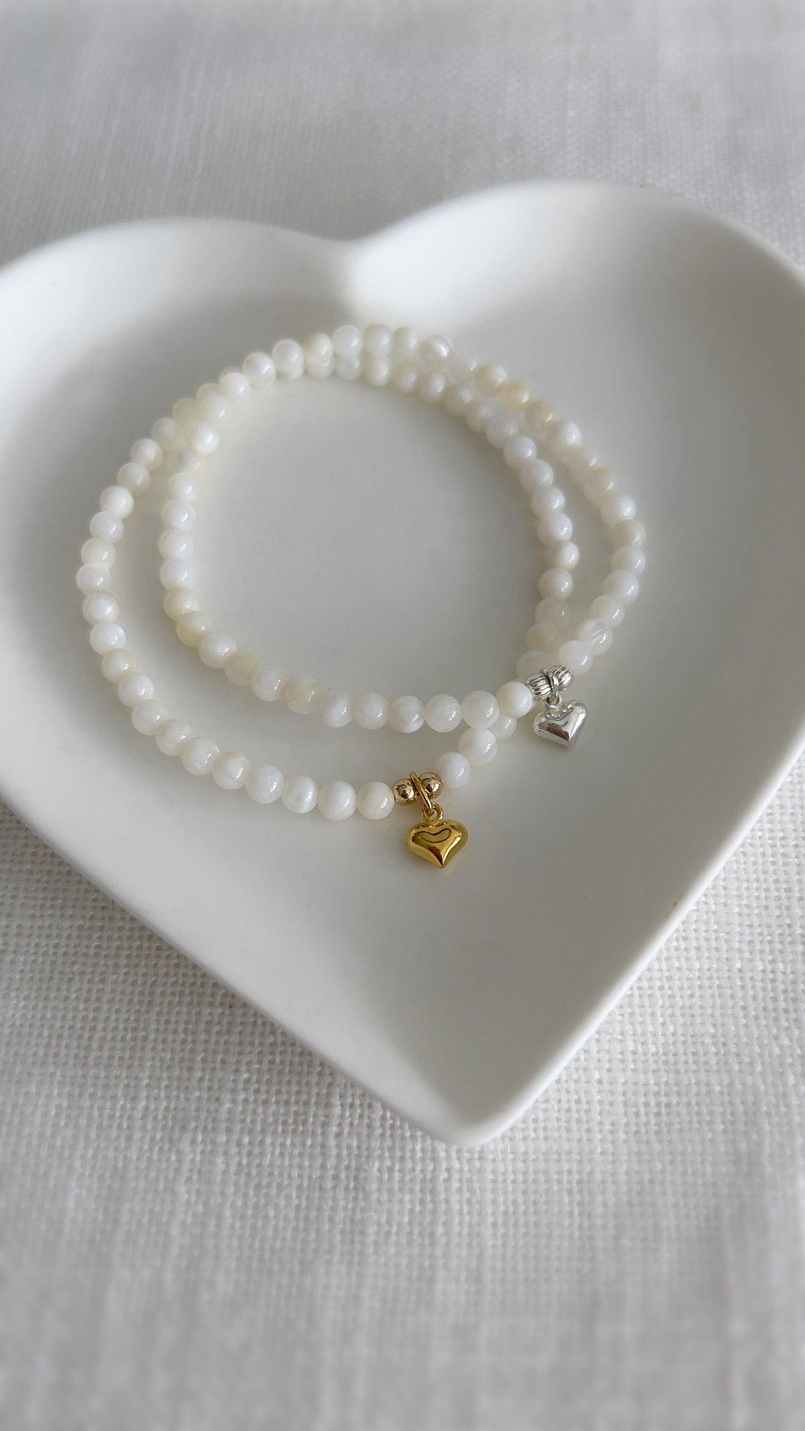A beautiful Mother of Pearl beaded bracelet, with a mini puff heart charm, hand threaded on high quality jewellery elastic for a comfortable stretch fit. Available with either a Gold vermeil or Sterling Silver finish.