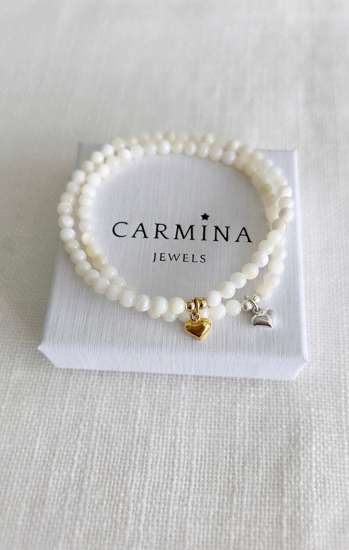 A beautiful Mother of Pearl beaded bracelet, with a mini puff heart charm, hand threaded on high quality jewellery elastic for a comfortable stretch fit. Available with either a Gold vermeil or Sterling Silver finish.