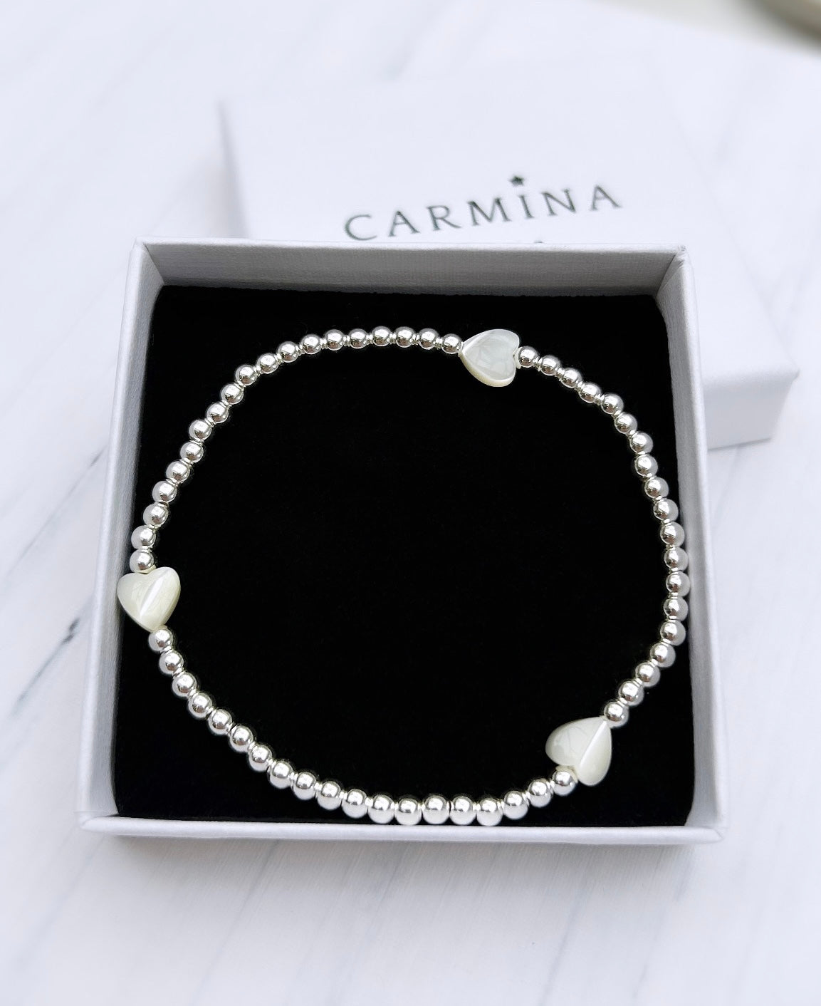 A Mother of Pearl heart bracelet with Sterling Silver beads, presented in a box with the Carmina brand visible.