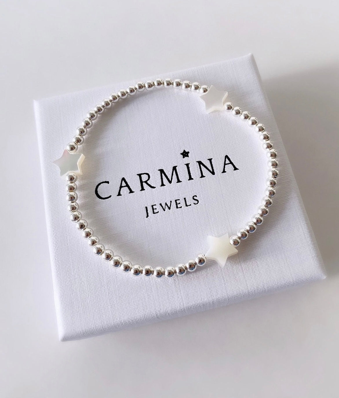A Mother of Pearl star bracelet with Sterling Silver beads, presented in a white box with 'CARMINA JEWELS' printed on it.