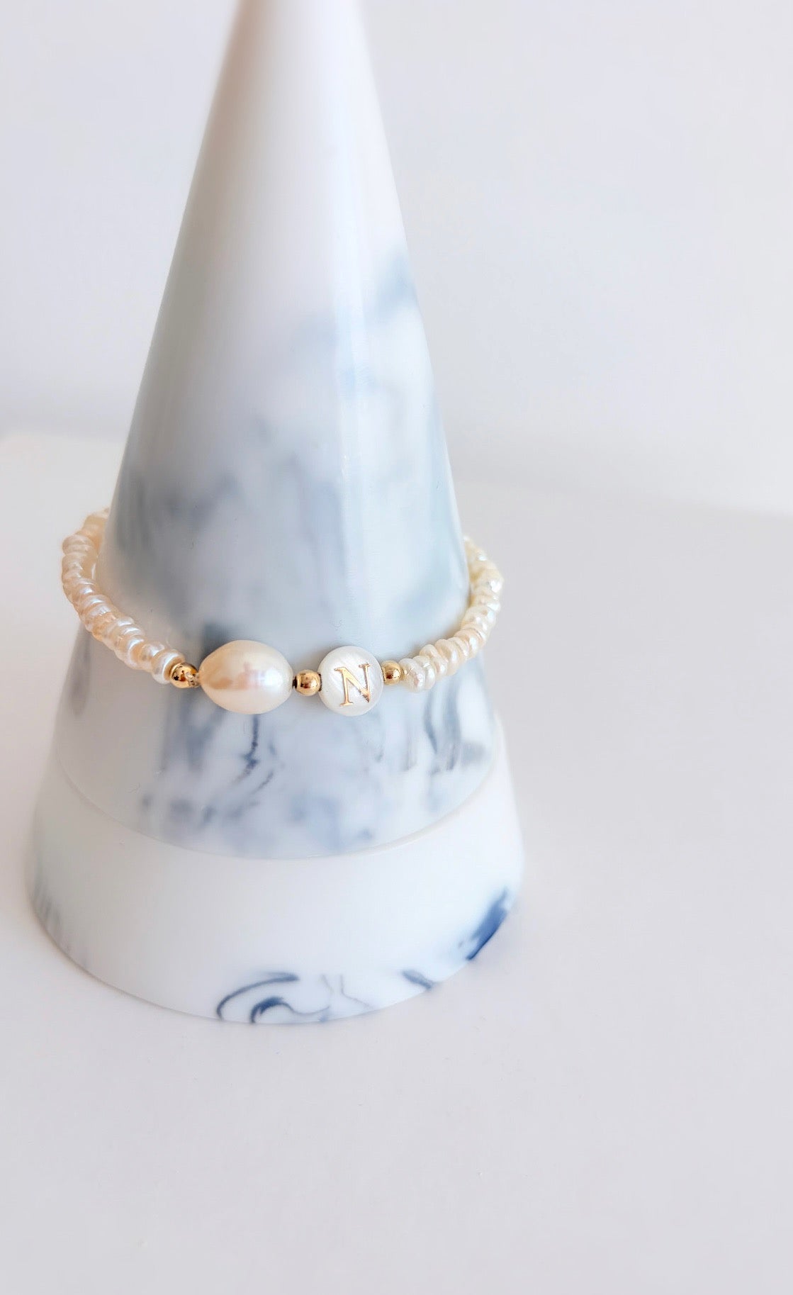 A delicate personalised stacking bracelet featuring a large baroque Pearl and a mother of pearl bead with your choice of initial. The bracelet is hand threaded with tiny off white Freshwater Pearls on a stretch cord, finished with a choice of either Sterling Silver or Gold filled spacer beads ~ a perfect stacker! 