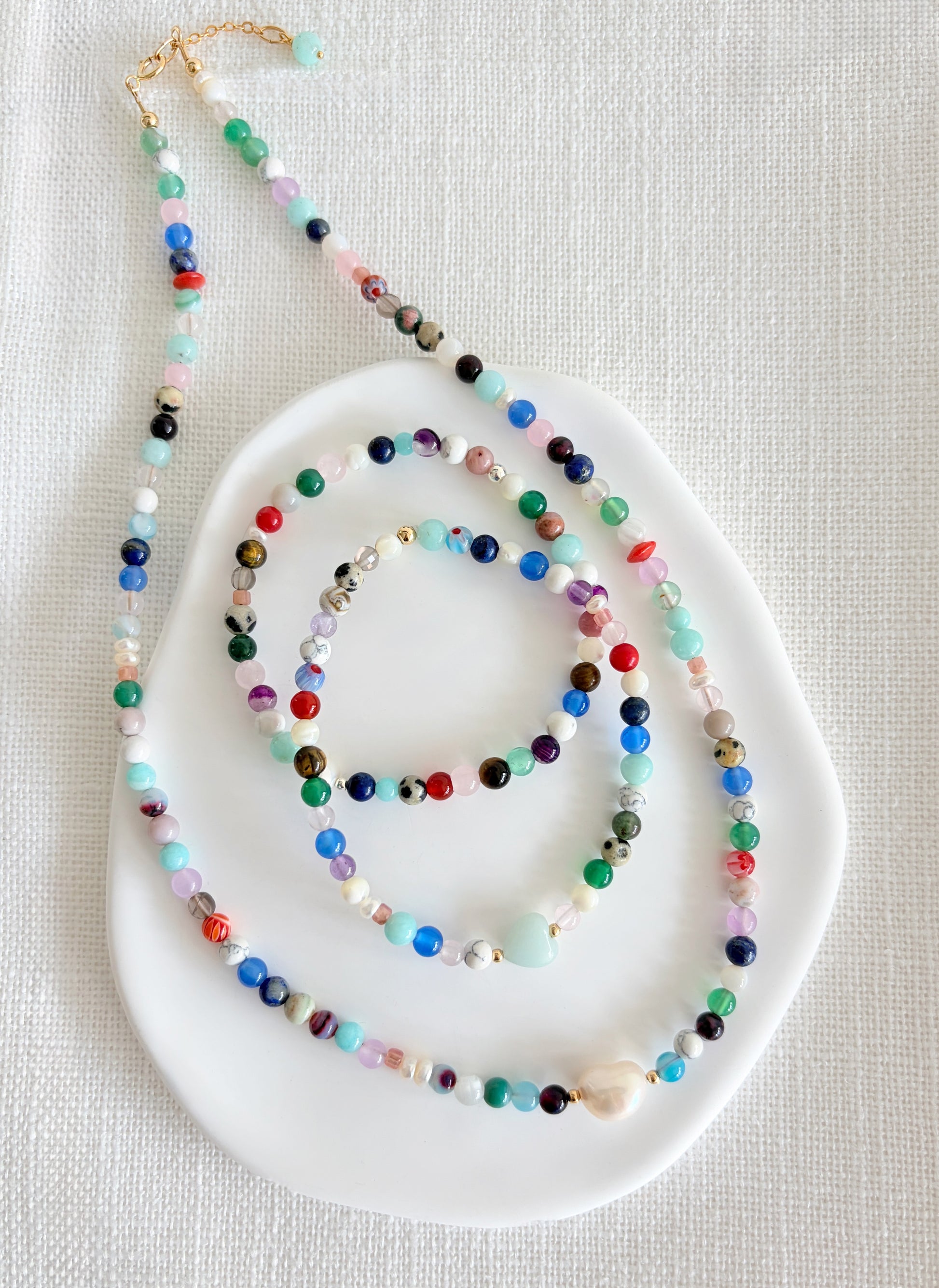 Featuring a glorious mix of vibrant semi precious beads, this beautiful bracelet is designed to add a touch of colour and elegance to any outfit. Choose between a charming Amazonite heart bead or an elegant baroque freshwater pearl as the centre.