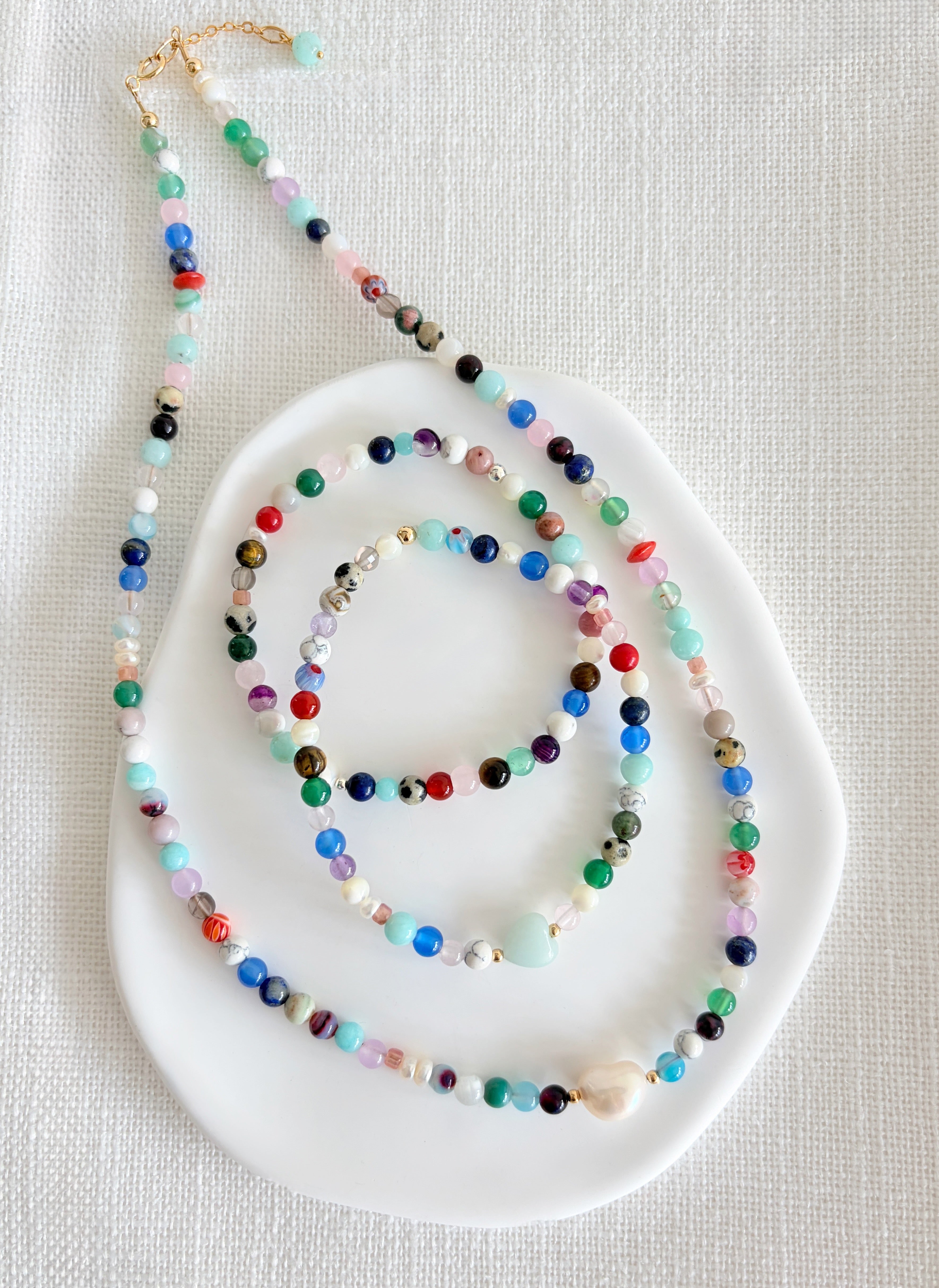 Featuring a glorious mix of vibrant semi precious beads, this beautiful bracelet is designed to add a touch of colour and elegance to any outfit. Choose between a charming Amazonite heart bead or an elegant baroque freshwater pearl as the centre.
