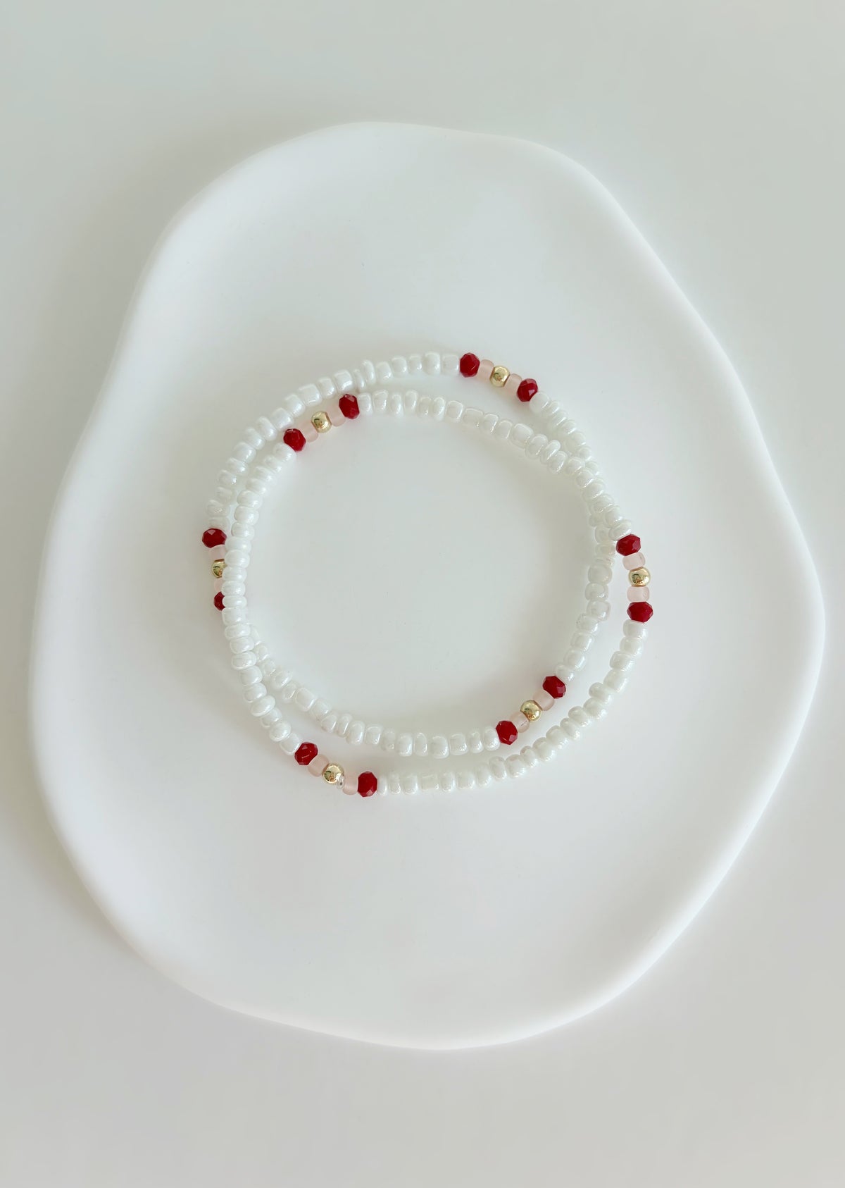 Pretty lustred glass seed bead bracelet, mixed with a subtle pattern of either aqua & pale grey or red/pink crystal glass beads and gold/silver spacer beads. Hand threaded on a high quality stretch cord. 
