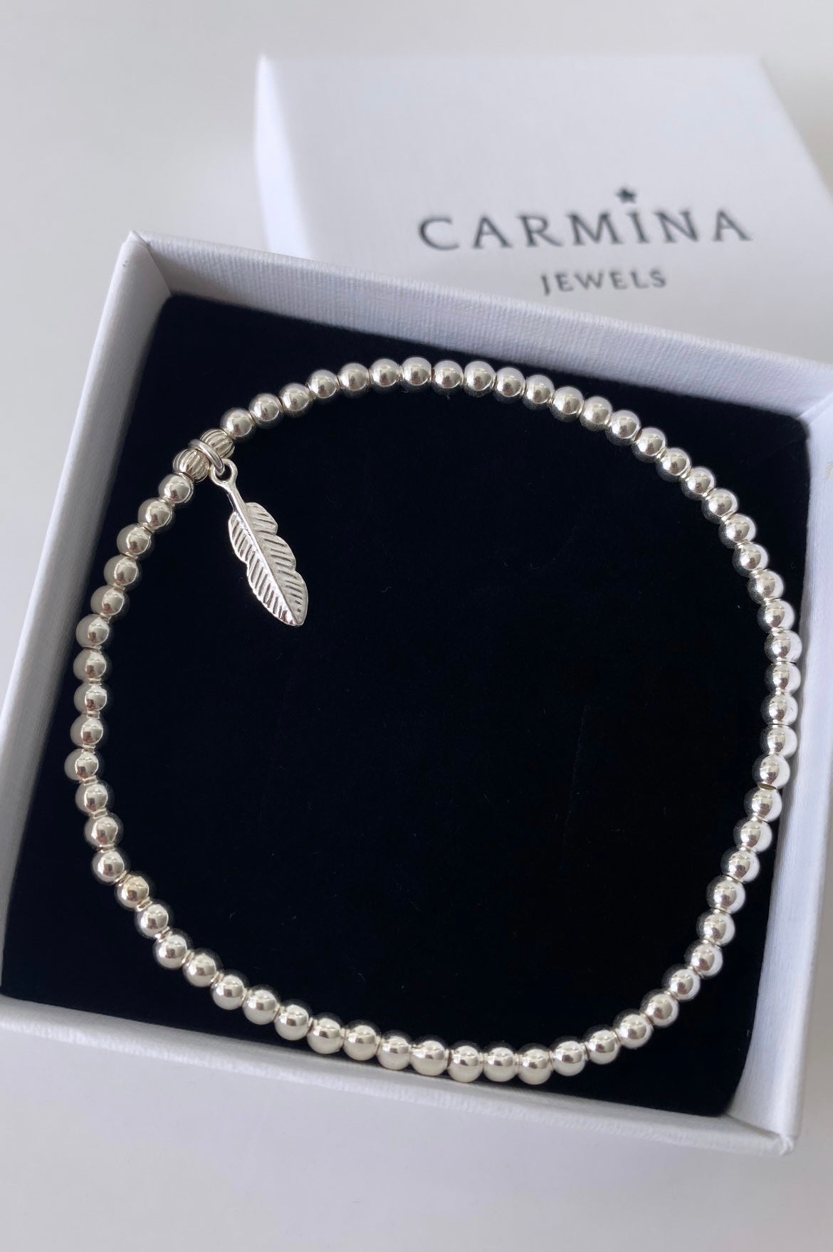 Beautiful Sterling Silver beaded bracelet on a stretch cord with a delicate silver Feather charm.
