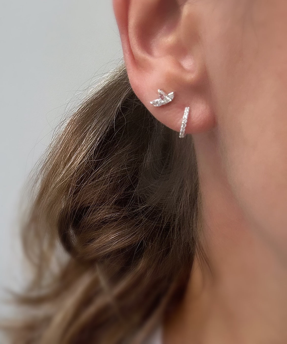 A pair of sterling silver huggie hoop earrings dotted with CZ crystals. 