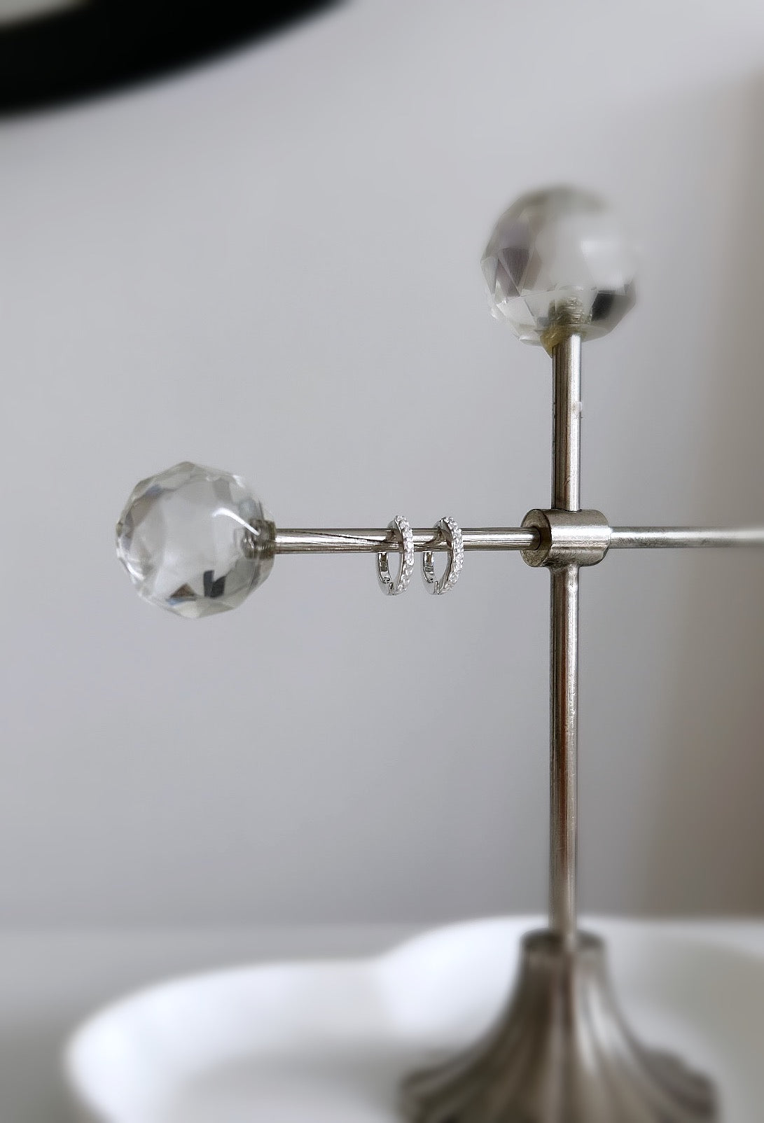 A pair of sterling silver huggie hoop earrings dotted with CZ crystals. 