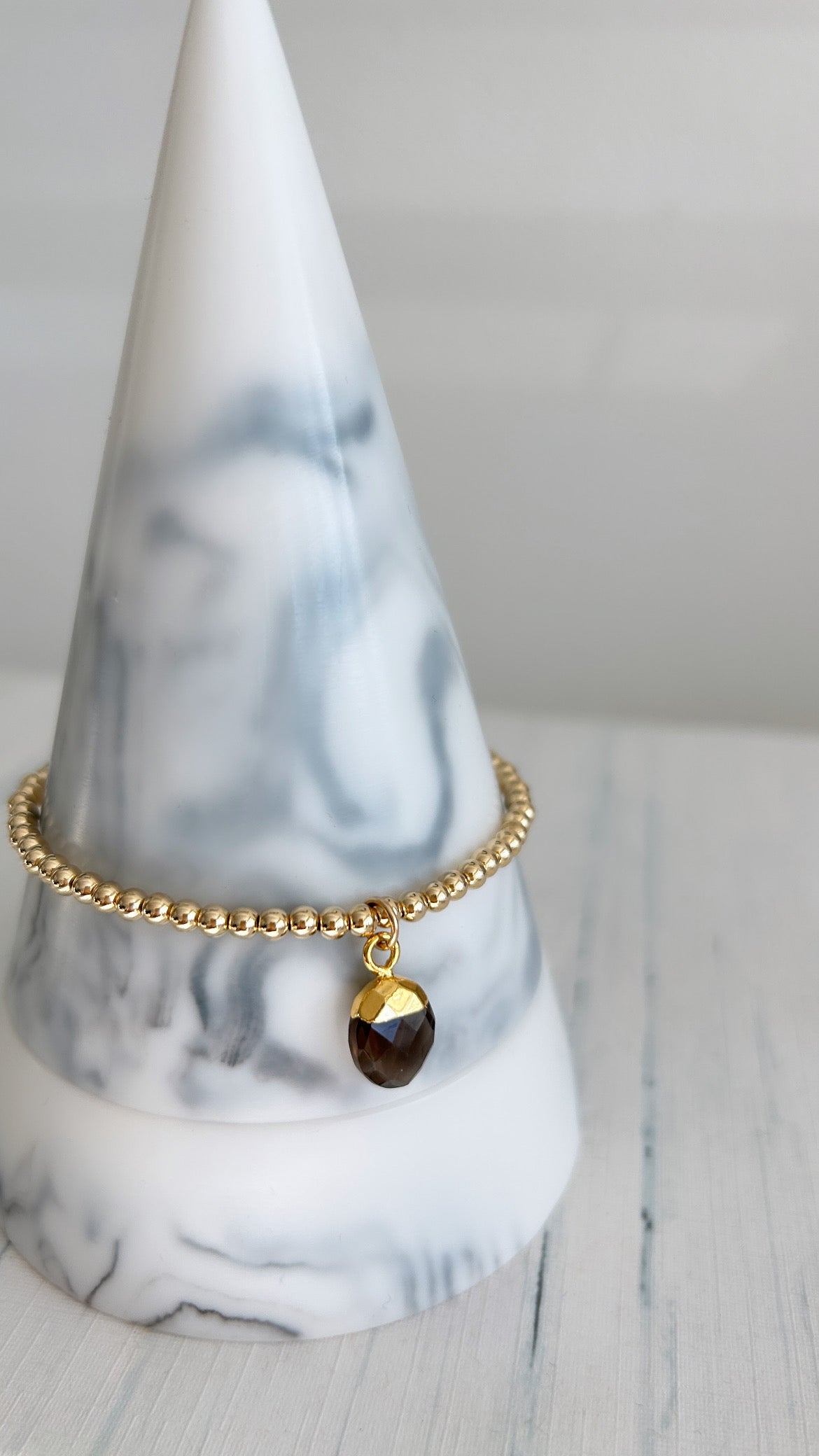 A gold charm bracelet featuring a Smoky Quartz pendant