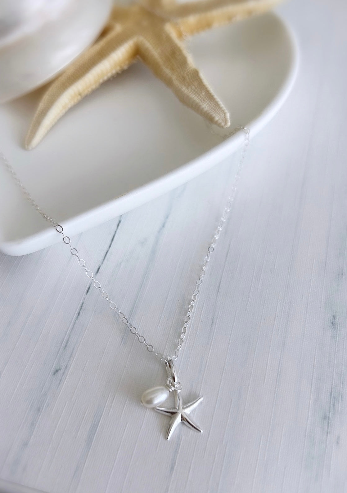 A pretty Silver pendant featuring a Sterling Silver Starfish charm, with a delicate Freshwater Rice Pearl. 