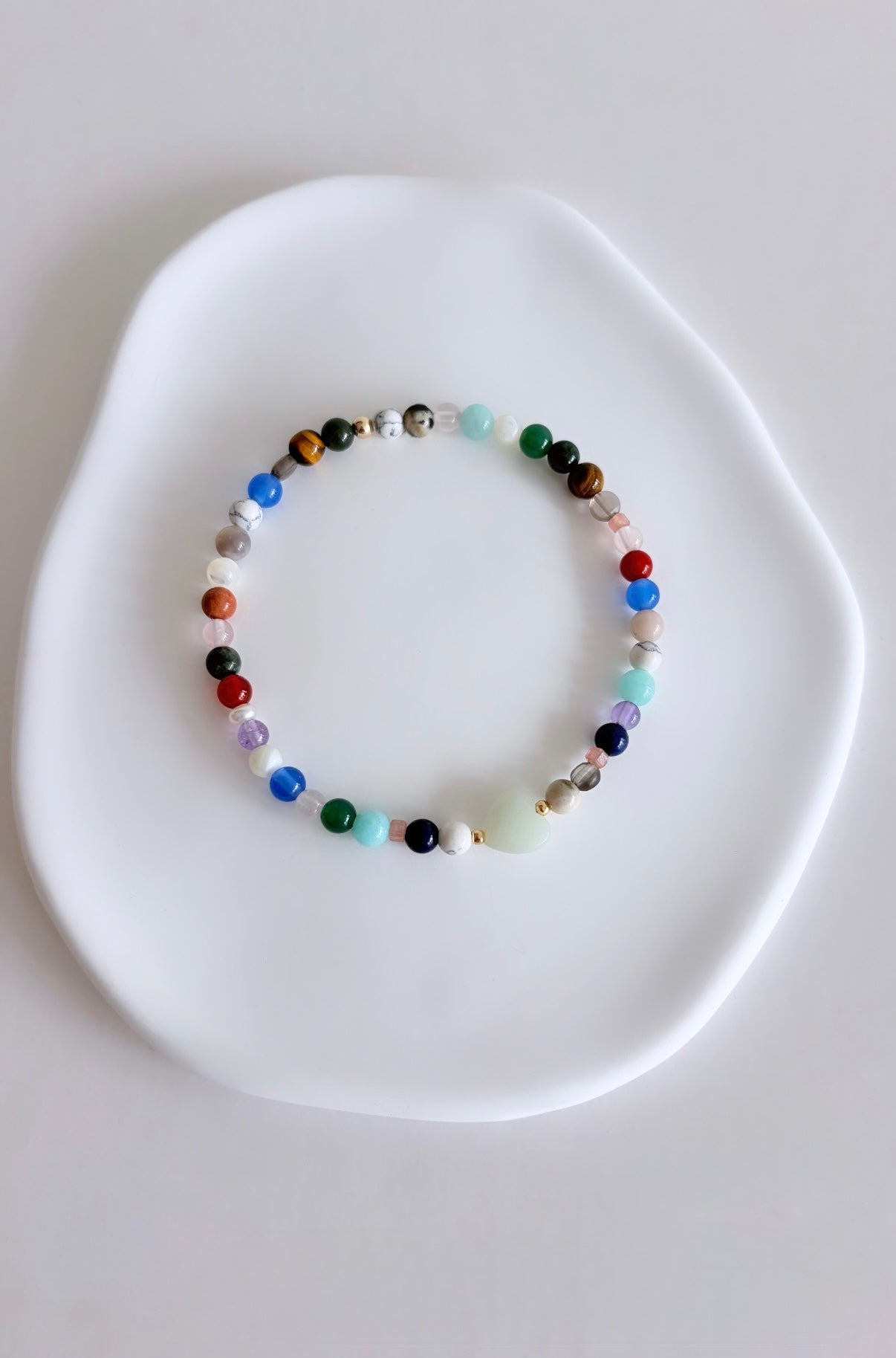 Featuring a glorious mix of vibrant semi precious beads, this beautiful bracelet is designed to add a touch of colour and elegance to any outfit. Choose between a charming Amazonite heart bead or an elegant baroque freshwater pearl as the centre.