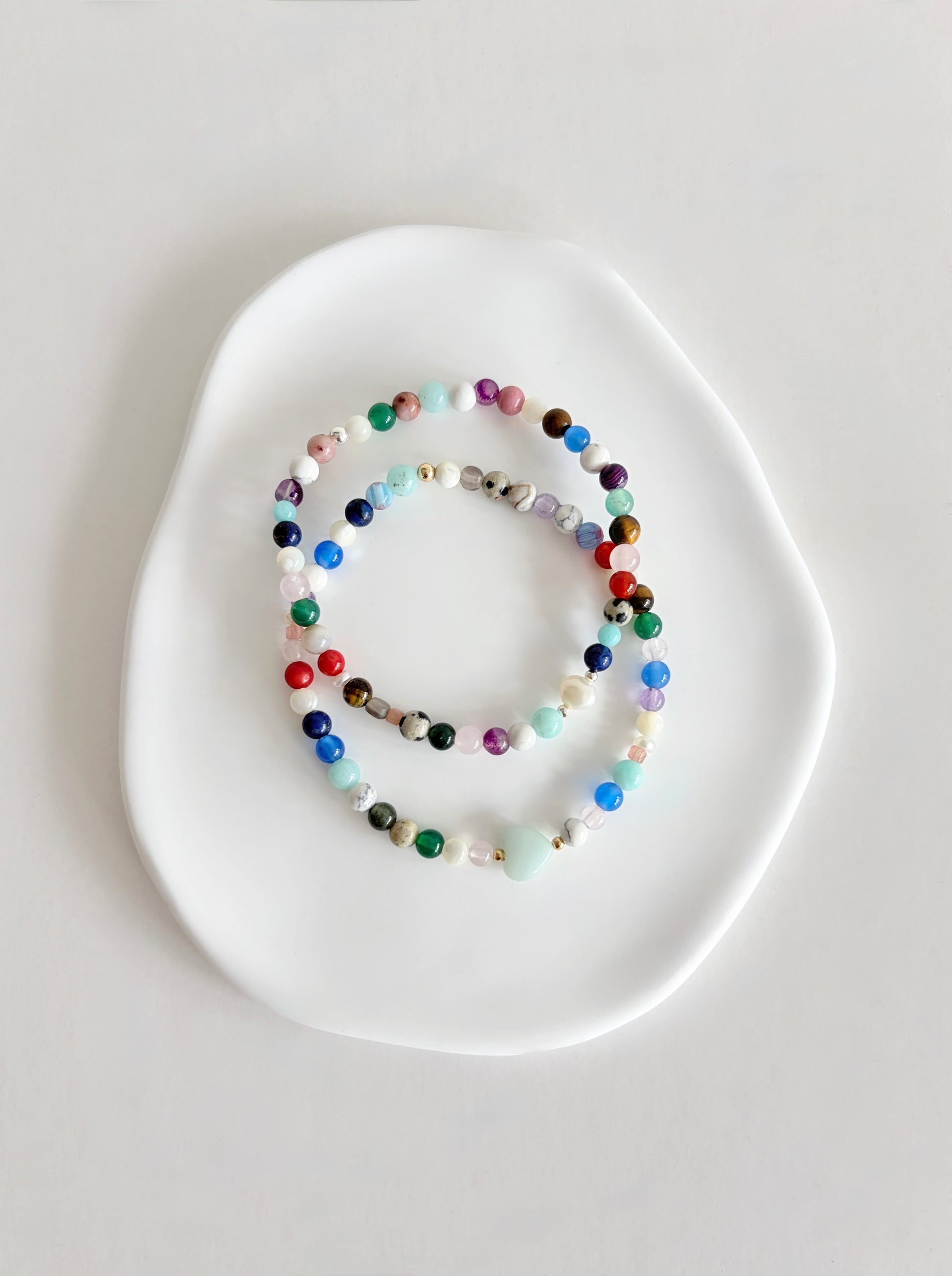 Featuring a glorious mix of vibrant semi precious beads, this beautiful bracelet is designed to add a touch of colour and elegance to any outfit. Choose between a charming Amazonite heart bead or an elegant baroque freshwater pearl as the centre.
