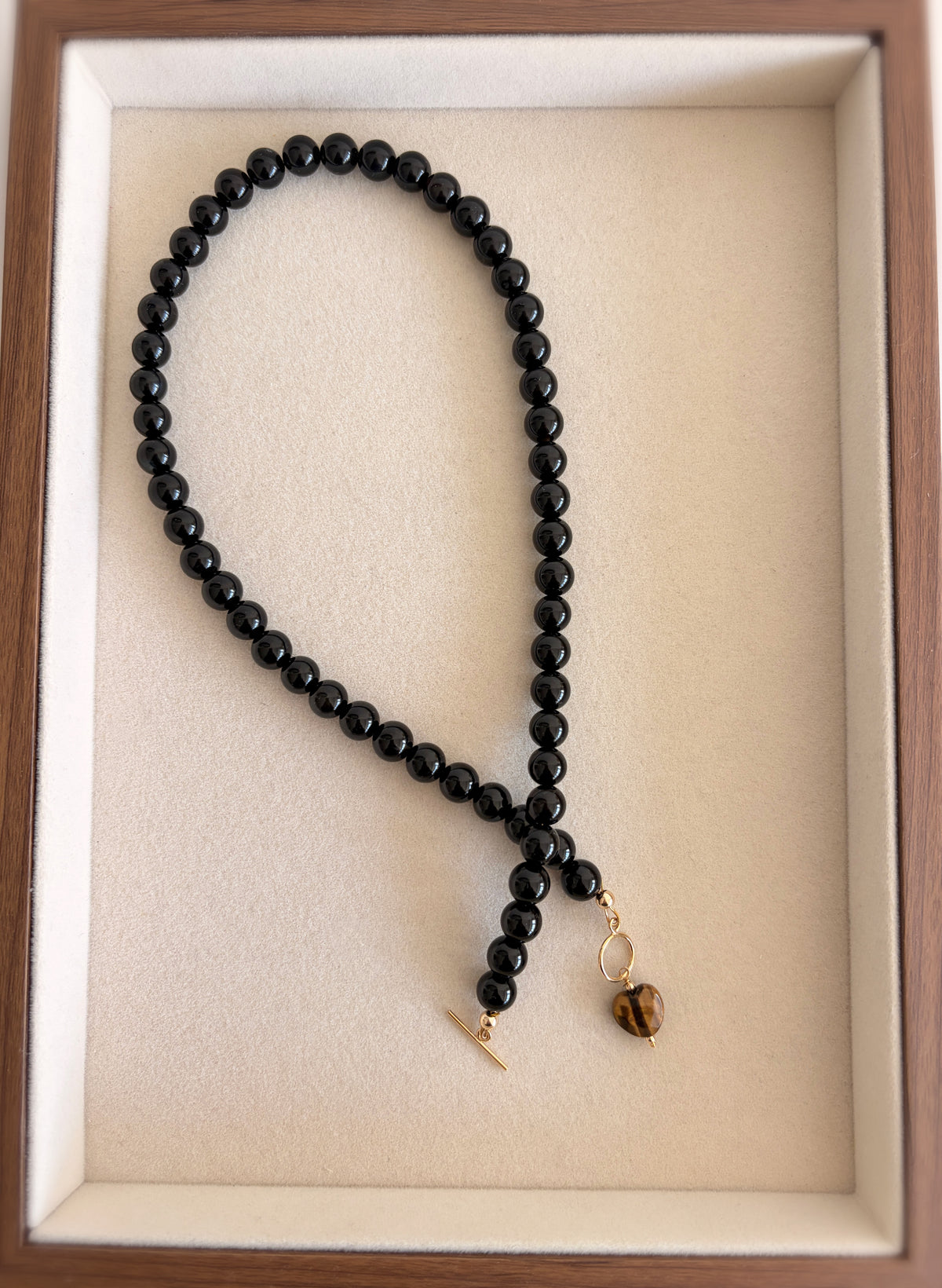 A stunning Black Onyx necklace featuring a faceted heart shaped Tiger’s Eye bead.

The necklace is finished with a toggle clasp, in either a Gold filled or Sterling Silver finish. The necklace length is approximately 17”