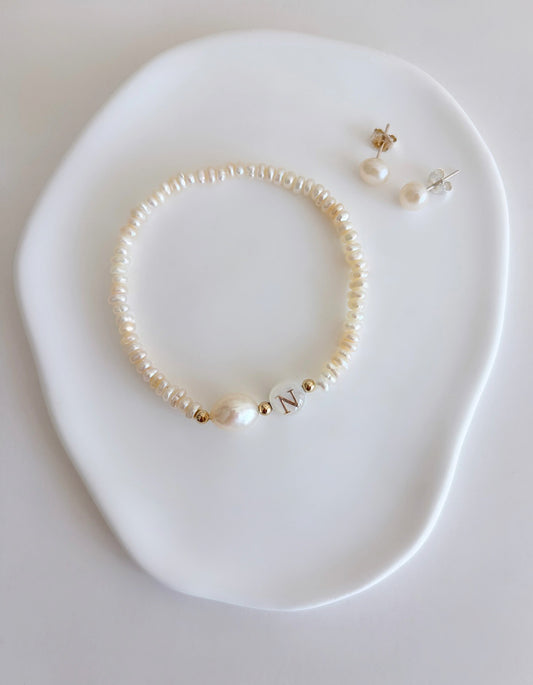 A delicate personalised stacking bracelet featuring a large baroque Pearl and a mother of pearl bead with your choice of initial. The bracelet is hand threaded with tiny off white Freshwater Pearls on a stretch cord, finished with a choice of either Sterling Silver or Gold filled spacer beads ~ a perfect stacker! 

