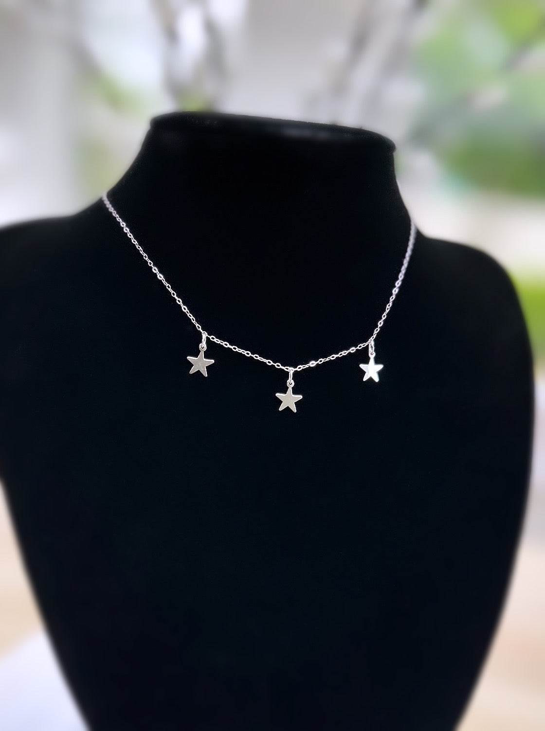 A silver starlight necklace with three silver star charms 